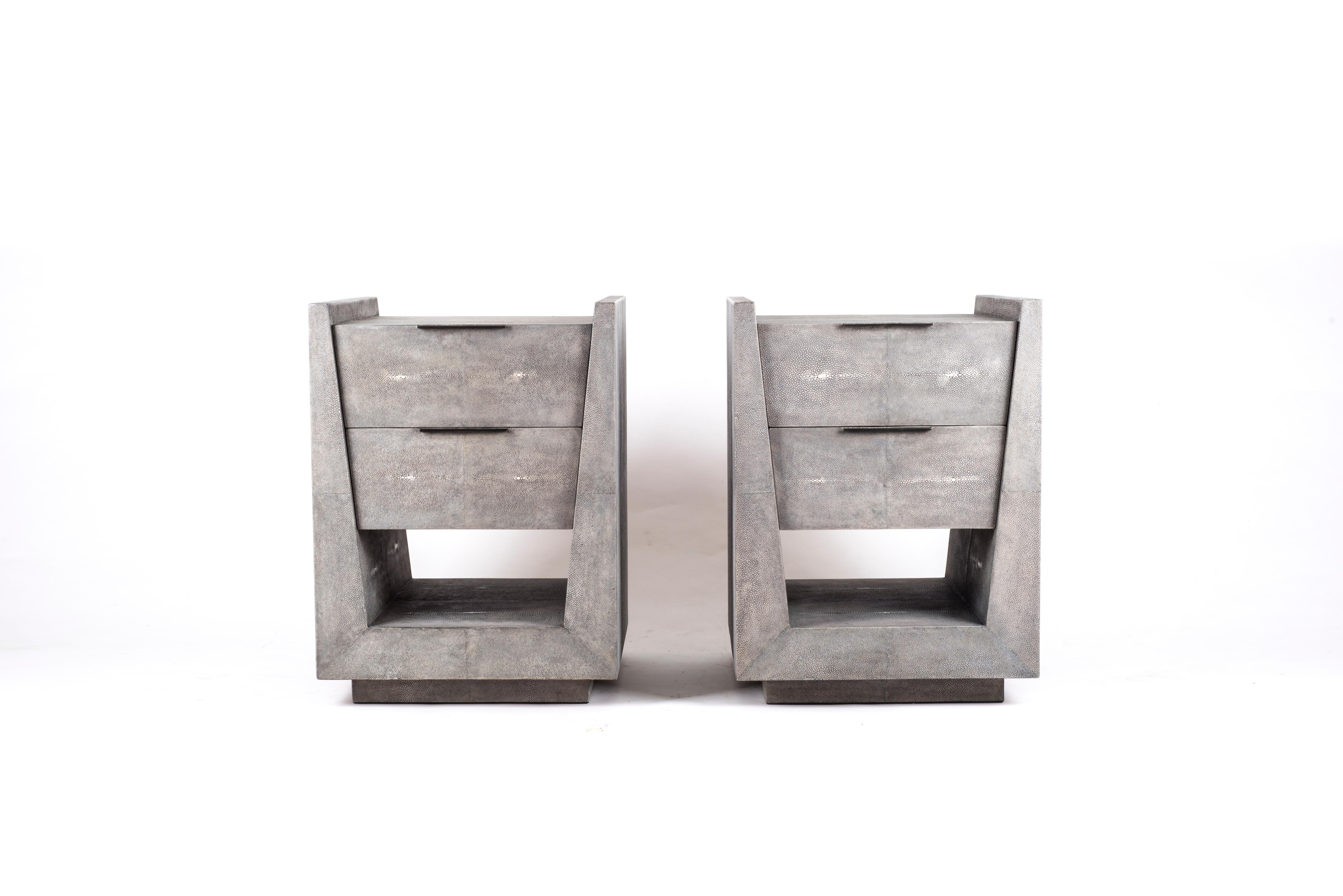 Le chevet Lola de R&Y Augousti est une pièce élégante avec sa géométrie subtile. Cette table de chevet est entièrement marquetée en galuchat gris avec de discrètes poignées plates en laiton bronze-patiné pour les tiroirs. Les tiroirs sont marquetés