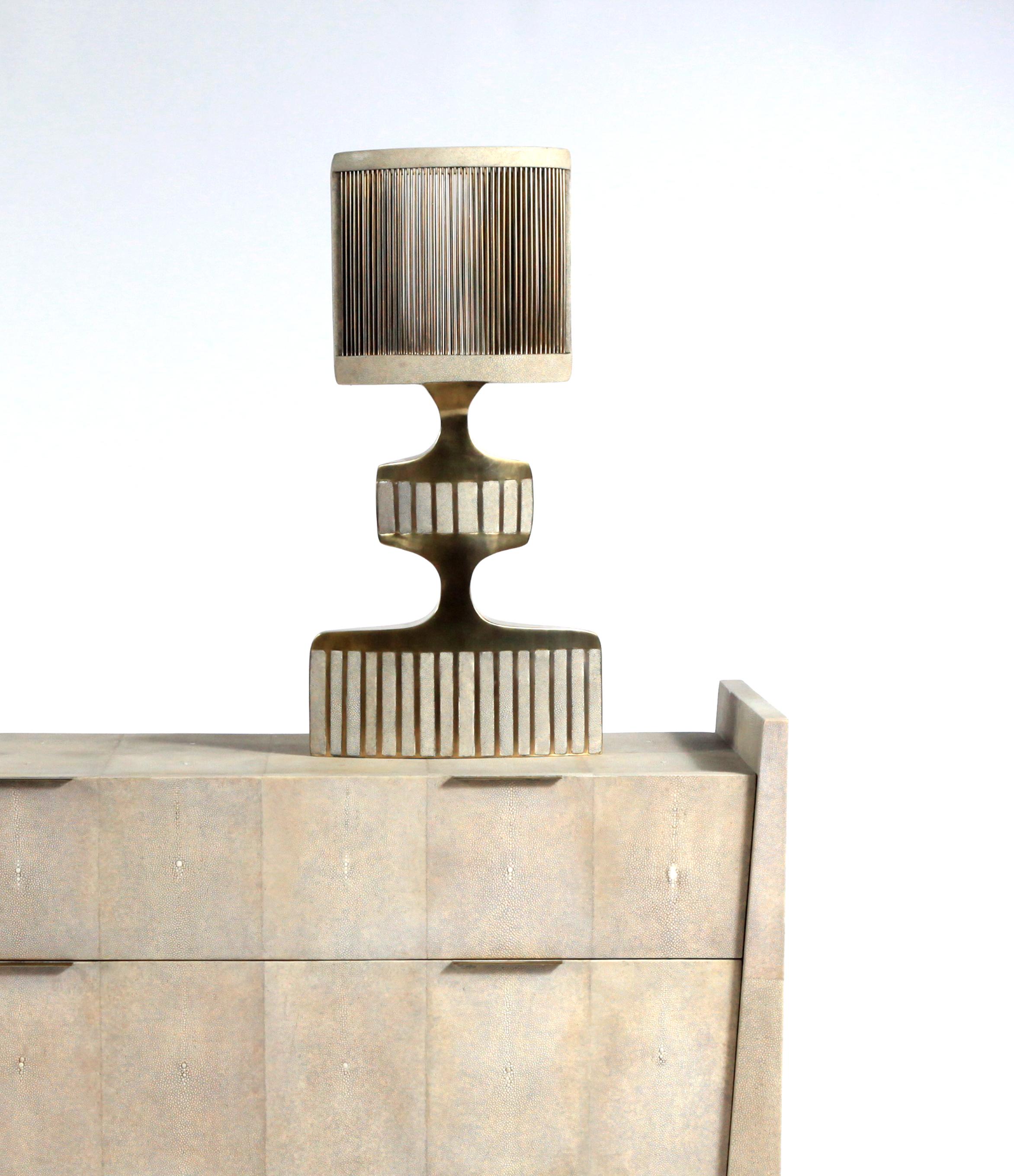 La commode Lola de R&Y Augousti est une pièce élégante avec sa géométrie subtile. Cette table de chevet est entièrement marquetée en galuchat crème avec de discrètes poignées plates en laiton bronze-patiné pour les tiroirs. Les tiroirs sont