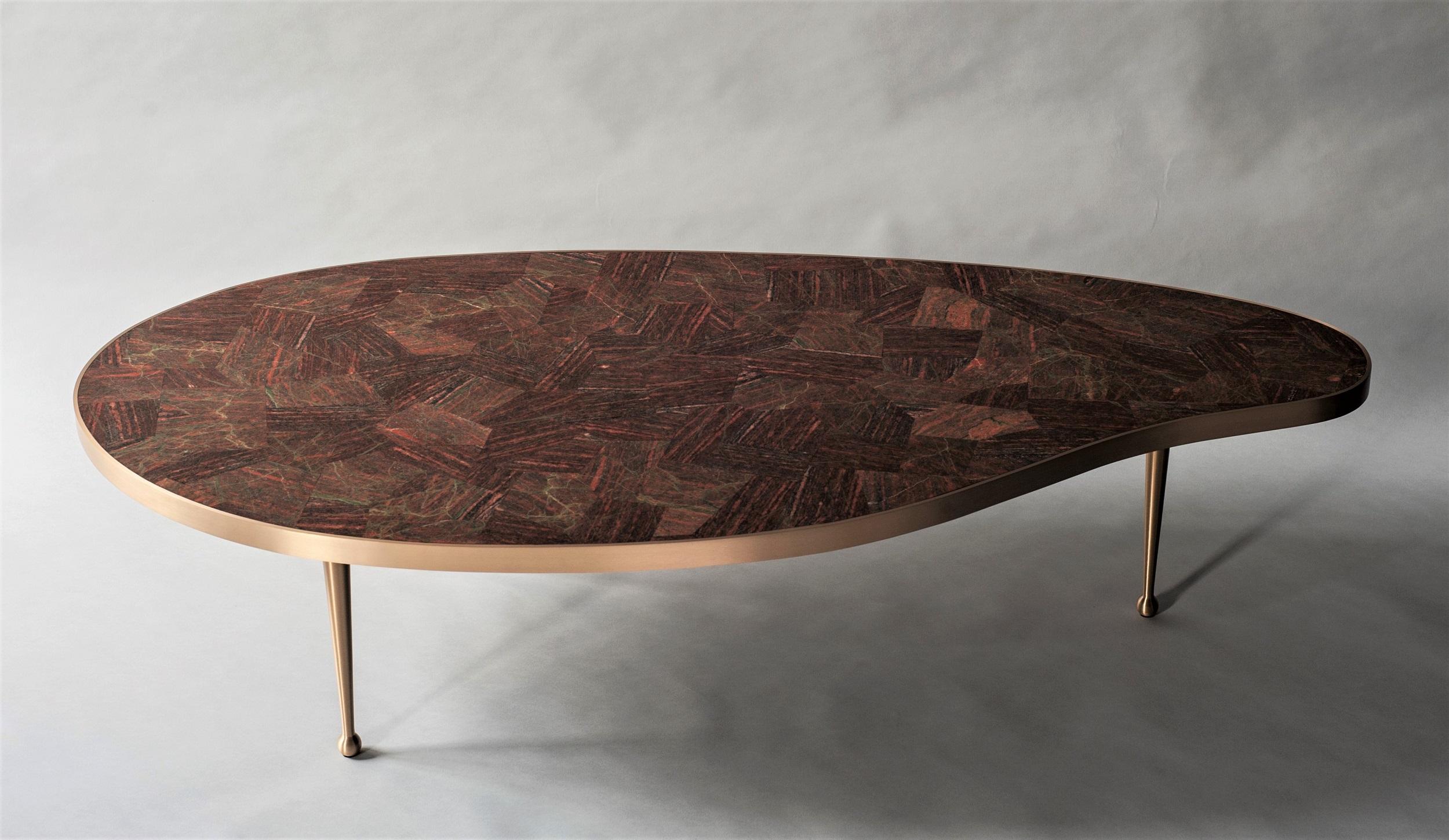 The bio-morphic shape and clean lines of the Lola coffee table by DeMuro Das were inspired by midcentury design. With a stone top made of polished, hand-laid Unakite, the table surface is both luxurious and functional. Hand-cast, solid satin brass