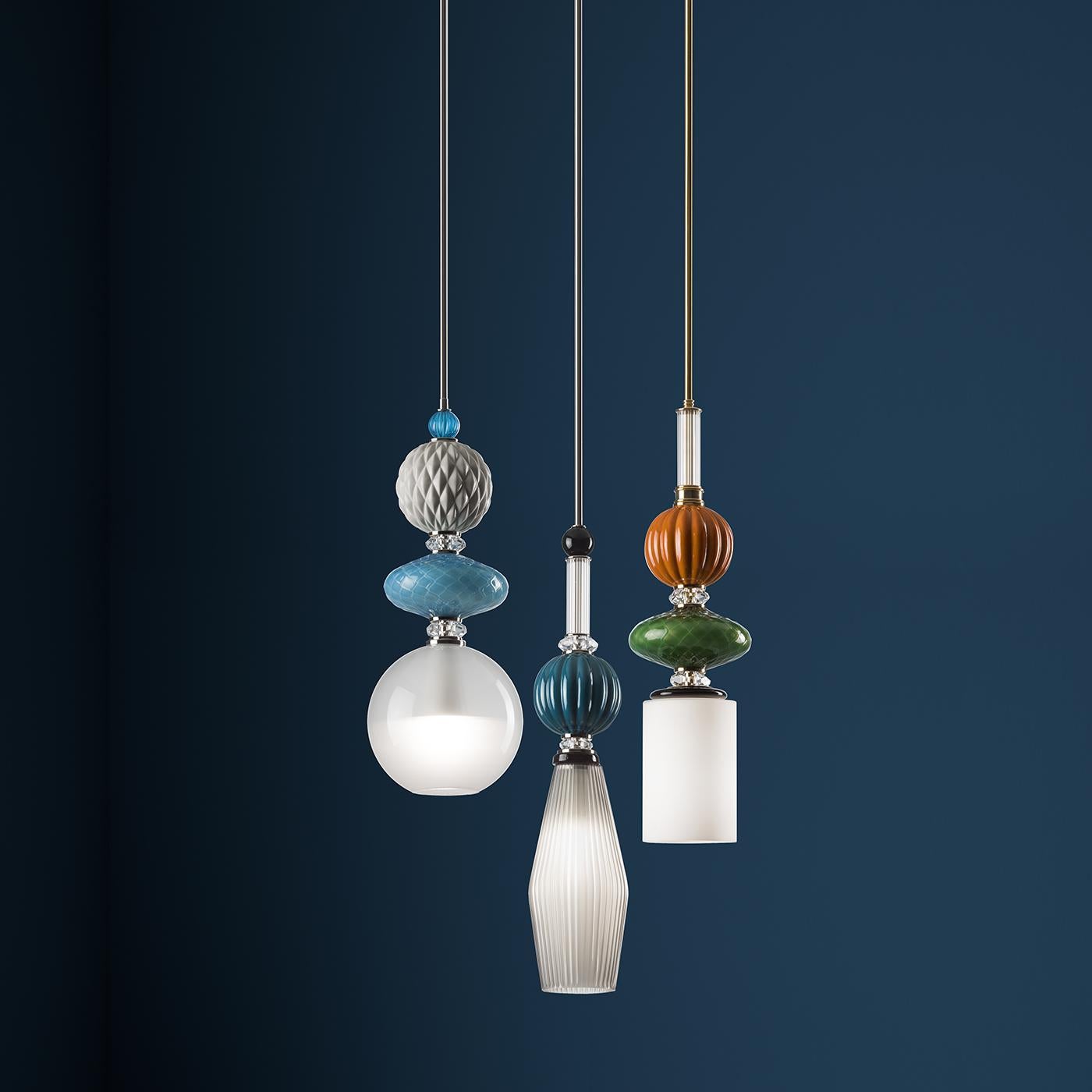 This exquisite pendant lamp showcases a rich and precious silhouette. The metal frame comes straight down from the ceiling from a cylindrical element to end in an eye-catching composition. The grooved glass diffuser slightly tapers downwards and
