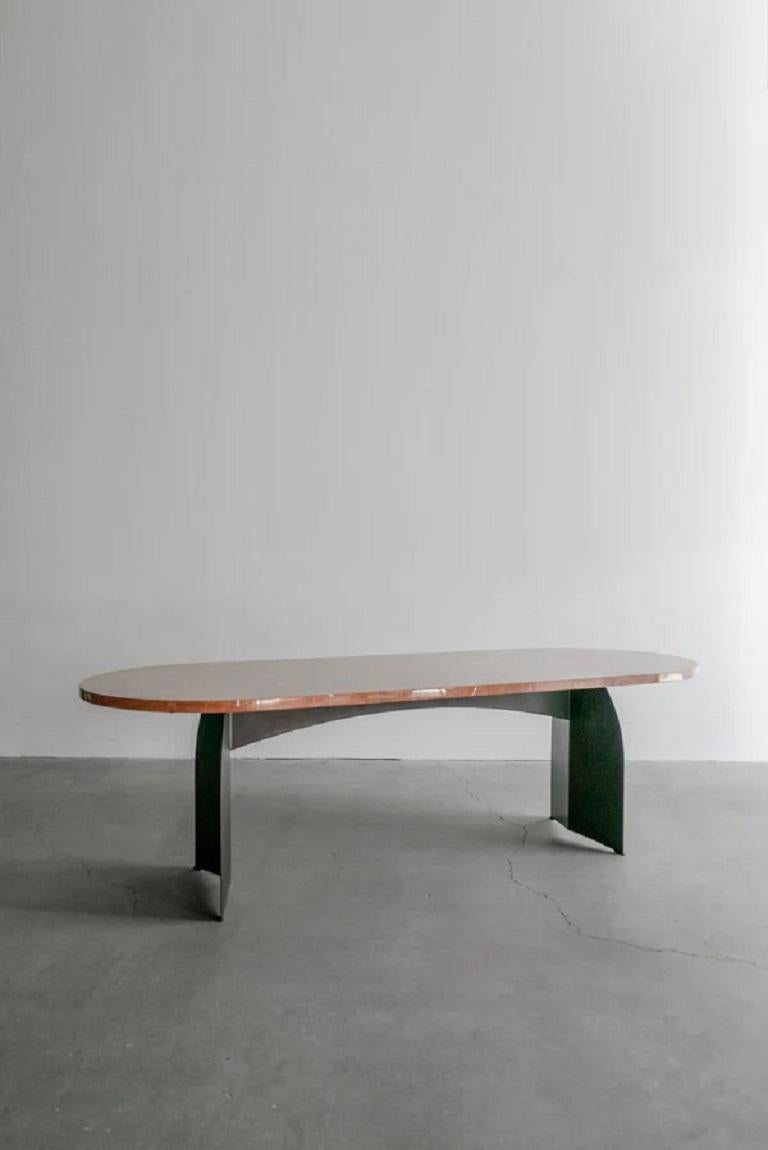 Cette table de salle à manger est fabriquée sur mesure à Los Angeles. Le marbre Rojo Alicante est taillé dans des plaques sélectionnées à la main. Le métal est plié à la forme et patiné. 
Le marbre présente naturellement des fissures, de petites