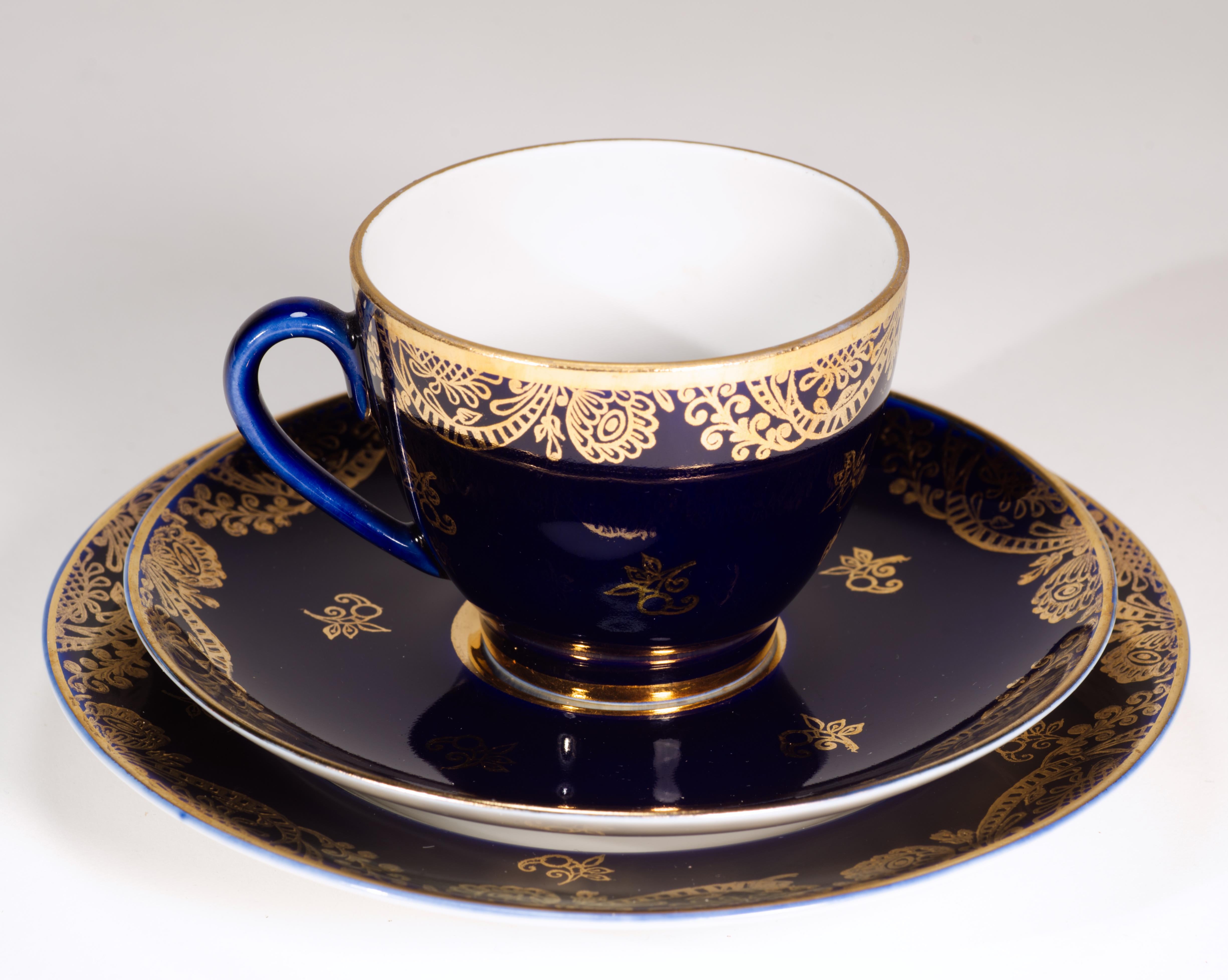  Il raro set di tazza, piattino e piatto da dessert presenta bordi dorati molto dettagliati e piccoli motivi floreali astratti su uno sfondo blu cobalto intenso. I bordi di tutti e tre i pezzi e le parti interne del piatto e dei piattini sono