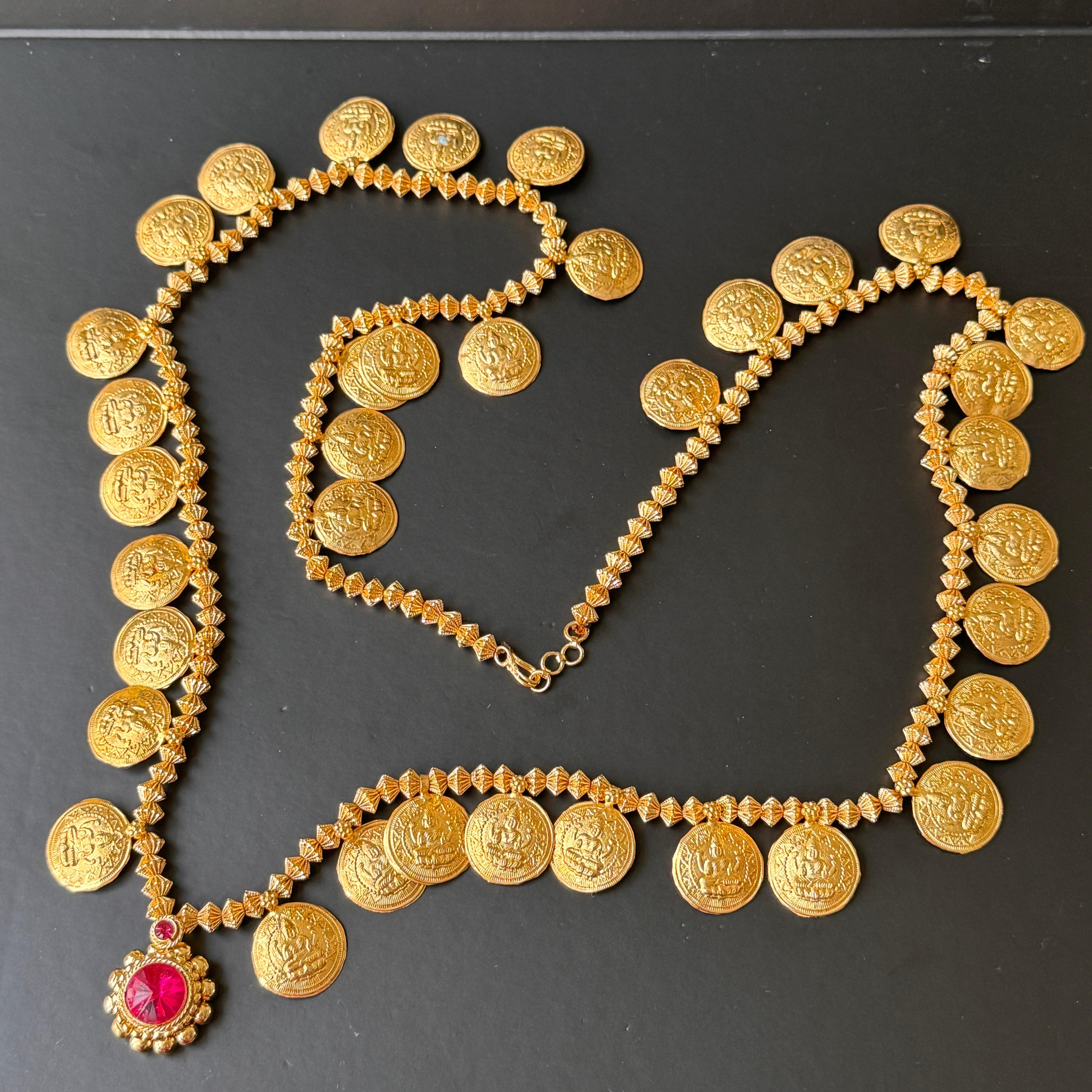 Questa splendida collana lunga è una bellissima fusione di artigianato e design. Caratterizzato da monete di dea stampate a mano e intervallate da piccole perle a nastro, crea un motivo sorprendente che emana eleganza e tradizione. La collana è