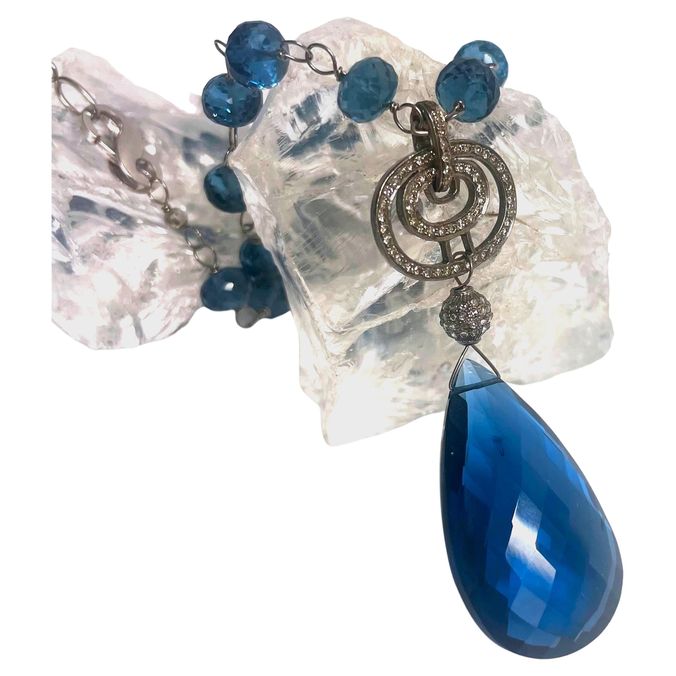 Description
The rich and exquisite London Blue color of this necklace doesn’t go unnoticed and makes a bold statement with its large teardrop London Blue quartz and pave diamond pendant. The individually wire wrapped stones and the small white gold