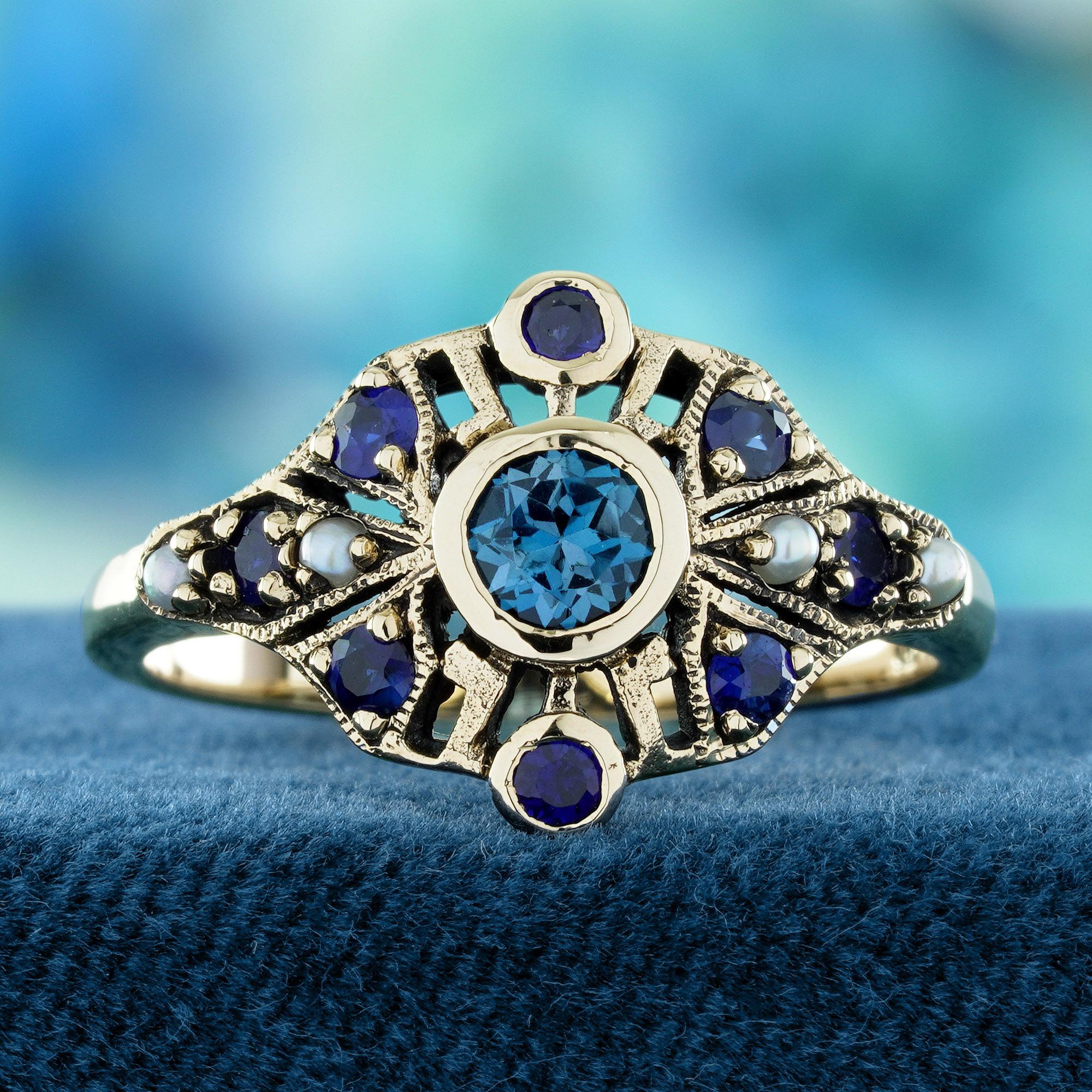 A stunning vintage-style ring featuring a natural London Blue Topaz at its center. Deep blue sapphires surround the main stone, adding depth and rich color. Delicately accented with natural pearls for a soft, elegant contrast. Crafted with intricate