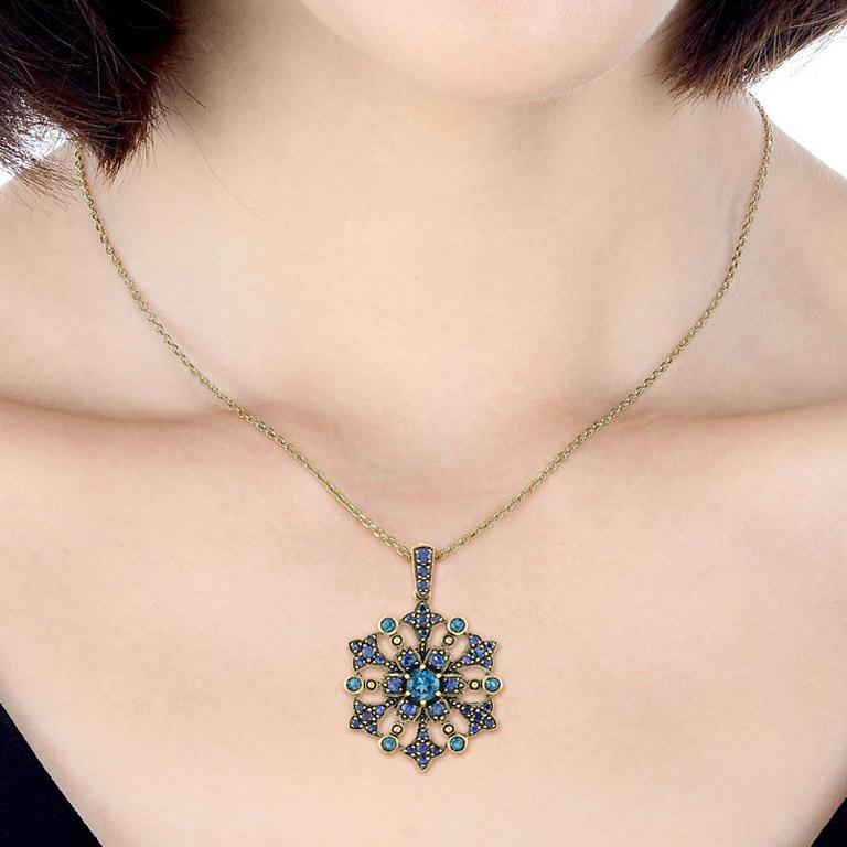 Inspired by Victorian antique era jewelry, this pendant is lovingly handcrafted in oxidized yellow gold. The centered London blue topaz is accented by blue sapphire to form a flower. All surrounding gemstones are blue sapphires and London blue