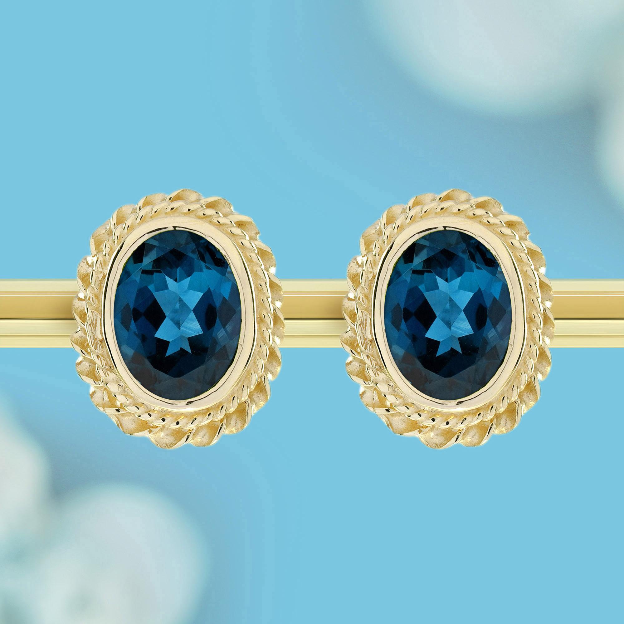 Ein atemberaubender ovaler Londoner Blautopas in der Mitte, umgeben von zarten Goldseilen, die eine schöne Form bilden. Der satte Blauton des Londoner Blautopas wird durch das warme Gold perfekt ergänzt, wodurch ein zeitloses und elegantes Design