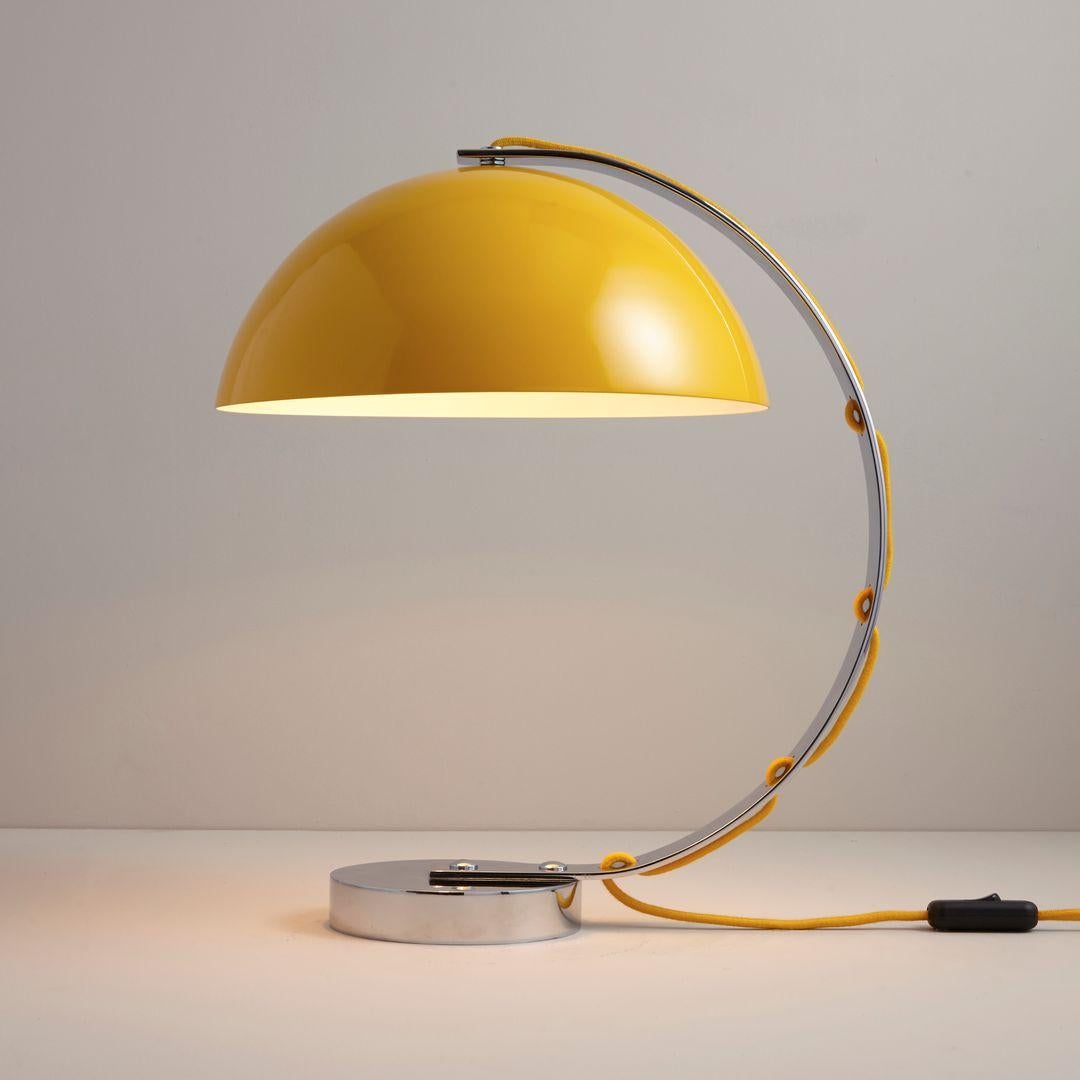 La lámpara de mesa London es una lámpara de escritorio con sabor retro. Presenta una pantalla semiesférica de aluminio hilado con una sólida base cromada. El flexo trenzado de algodón se entreteje a través del brazo cromado curvado para un acabado