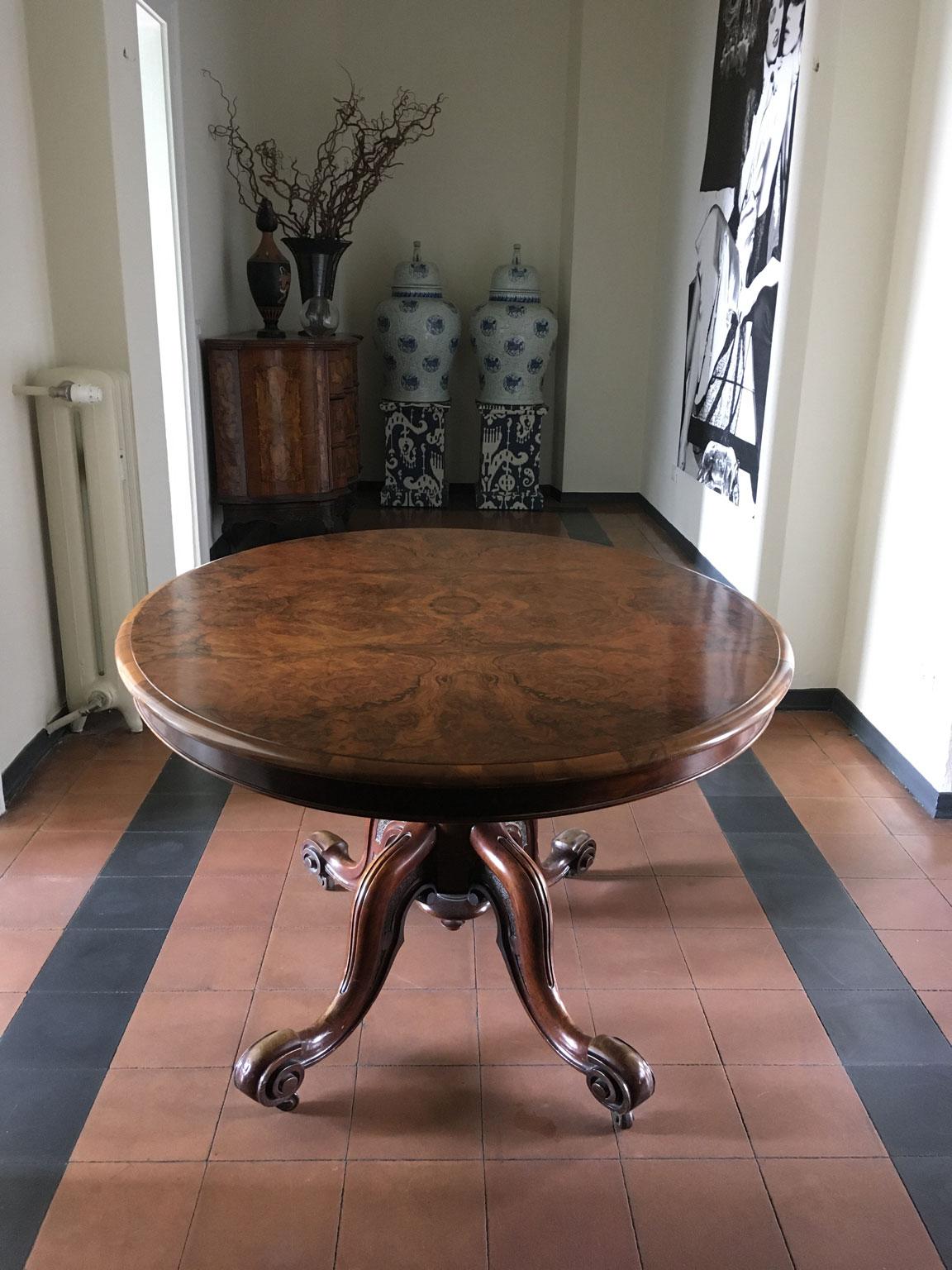 This elegant tip top oval table, has the top hand made  in a selection of walnut and the central foot in hand-carved briar wood.  
Under the top there is the label signed 