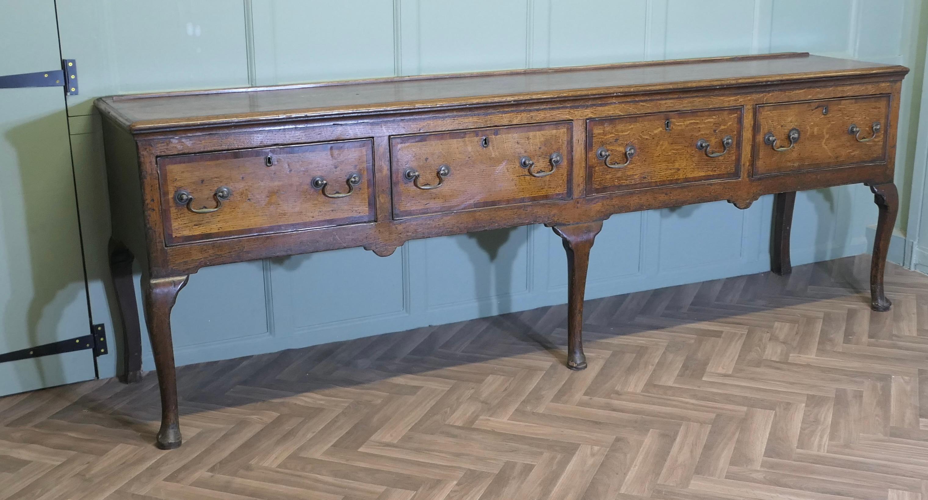 Long 18th Century Country Oak Dresser Base

A beautiful Country made Oak Dresser Base it is made from thick heavy Oak it has four very deep drawers and stands on sturdy Pad Feet  
The dresser has beautiful patination and the condition is good, this