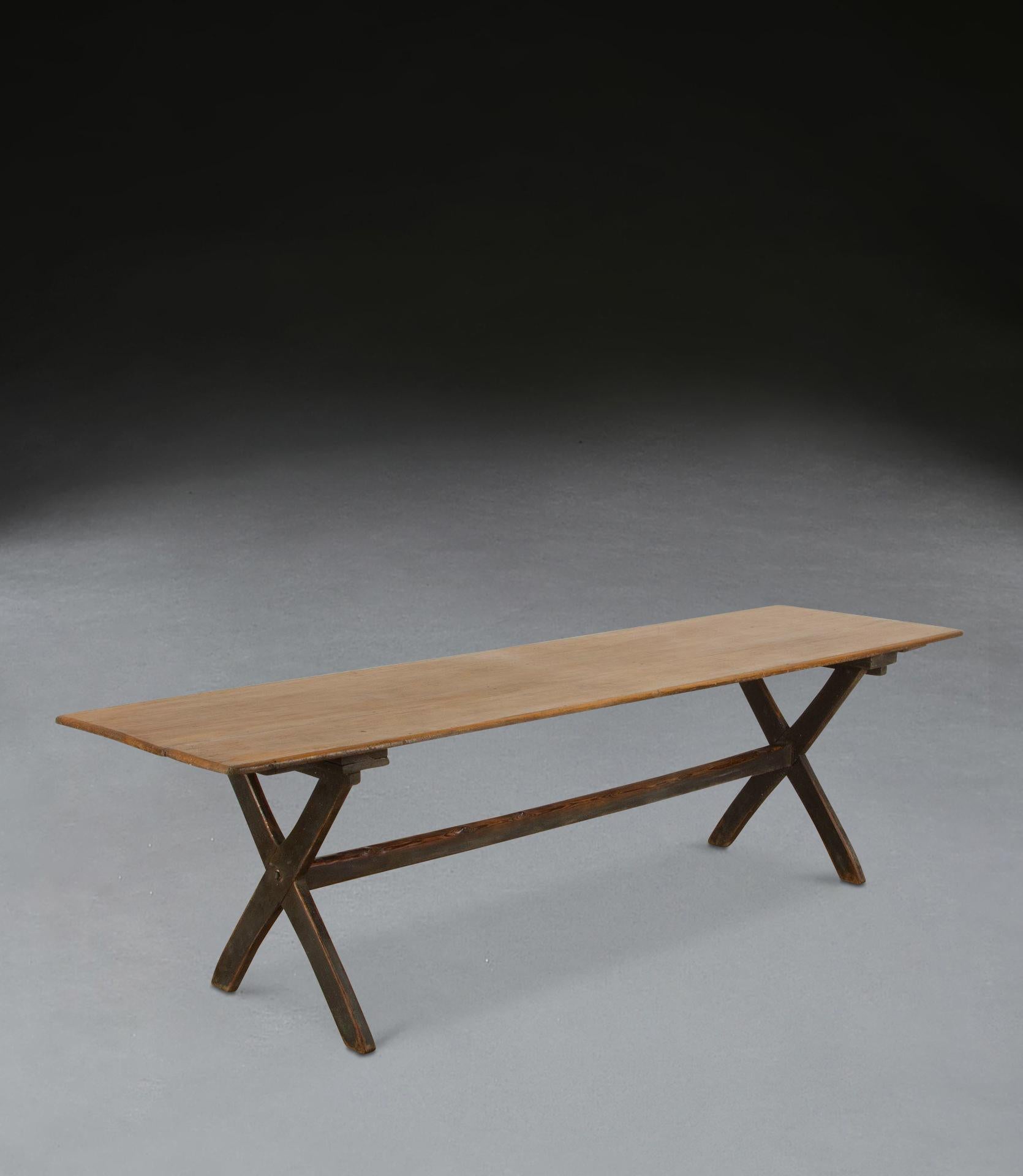 Raro artículo de mobiliario rústico del siglo XIX, una mesa de taberna de buen tamaño y estabilidad, el tablero con buen color y superficie, apoyado sobre dos bases en forma de X unidas con una camilla central, todo ello conservando su pintura