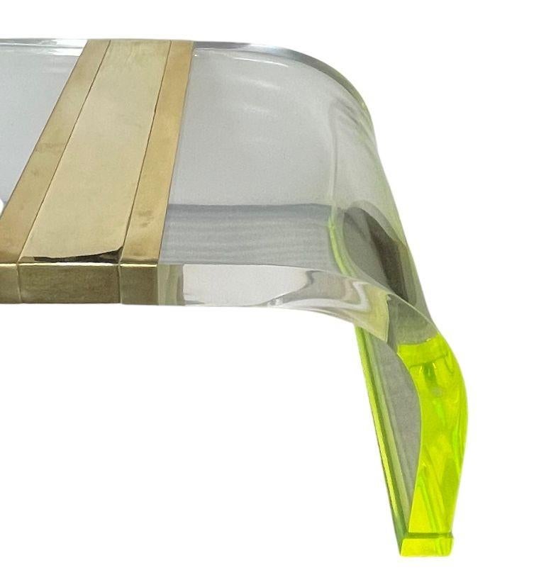 Striking and sculptural, this extra-long acrylic coffee table with curved legs is a bold statement piece from the 1980's. Crafted in thick 2-inch clear acrylic, it features gracefully curved legs with fluorescent green accents that add a pop of