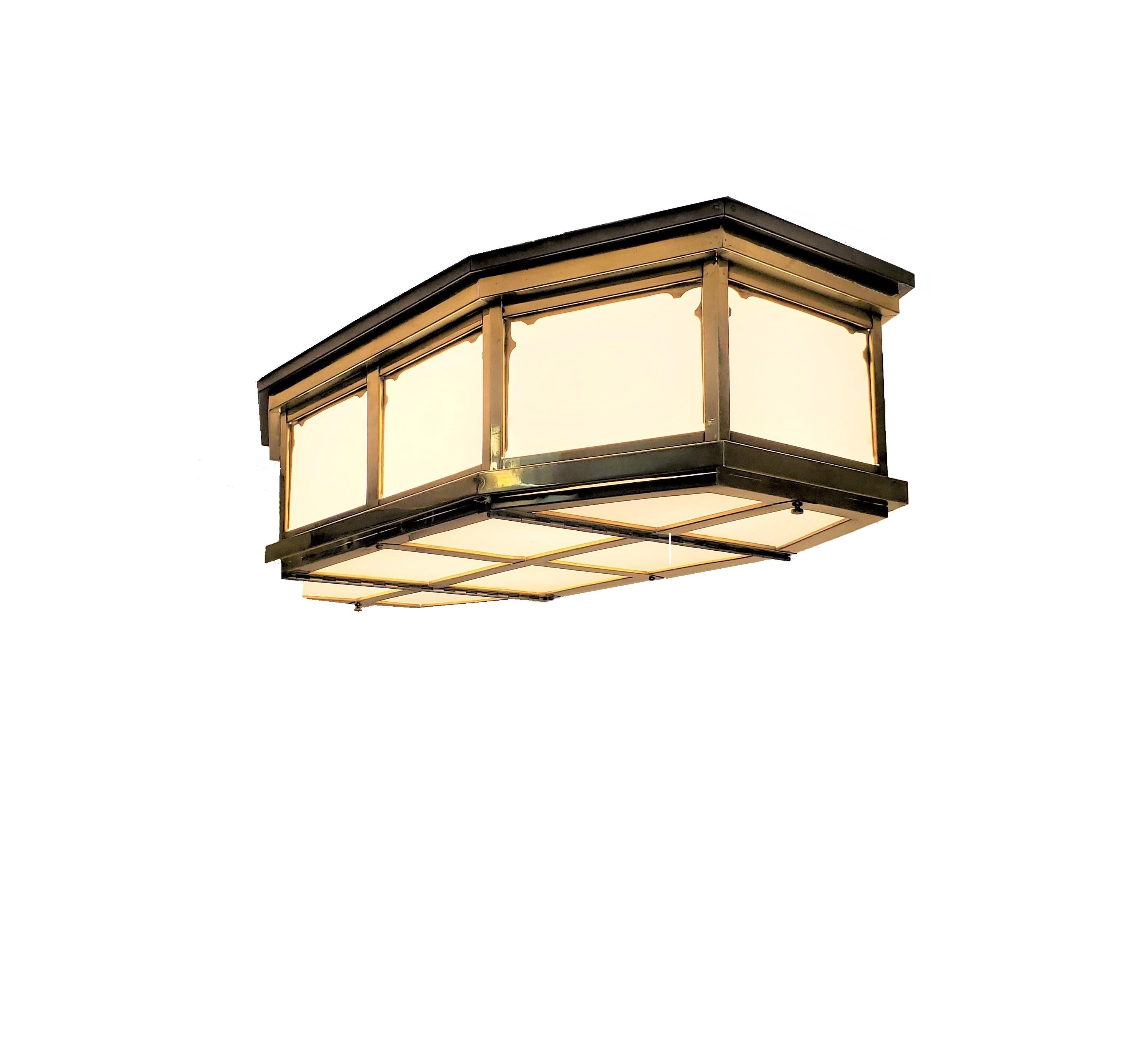 An elongated octagonal Mid-Century Modern glass flush mounted fixture with brass stepped design frame. The eight sided shape features opaque white glass panel insets each circumvented by a decorative frame surround and ending with a grid like, eight