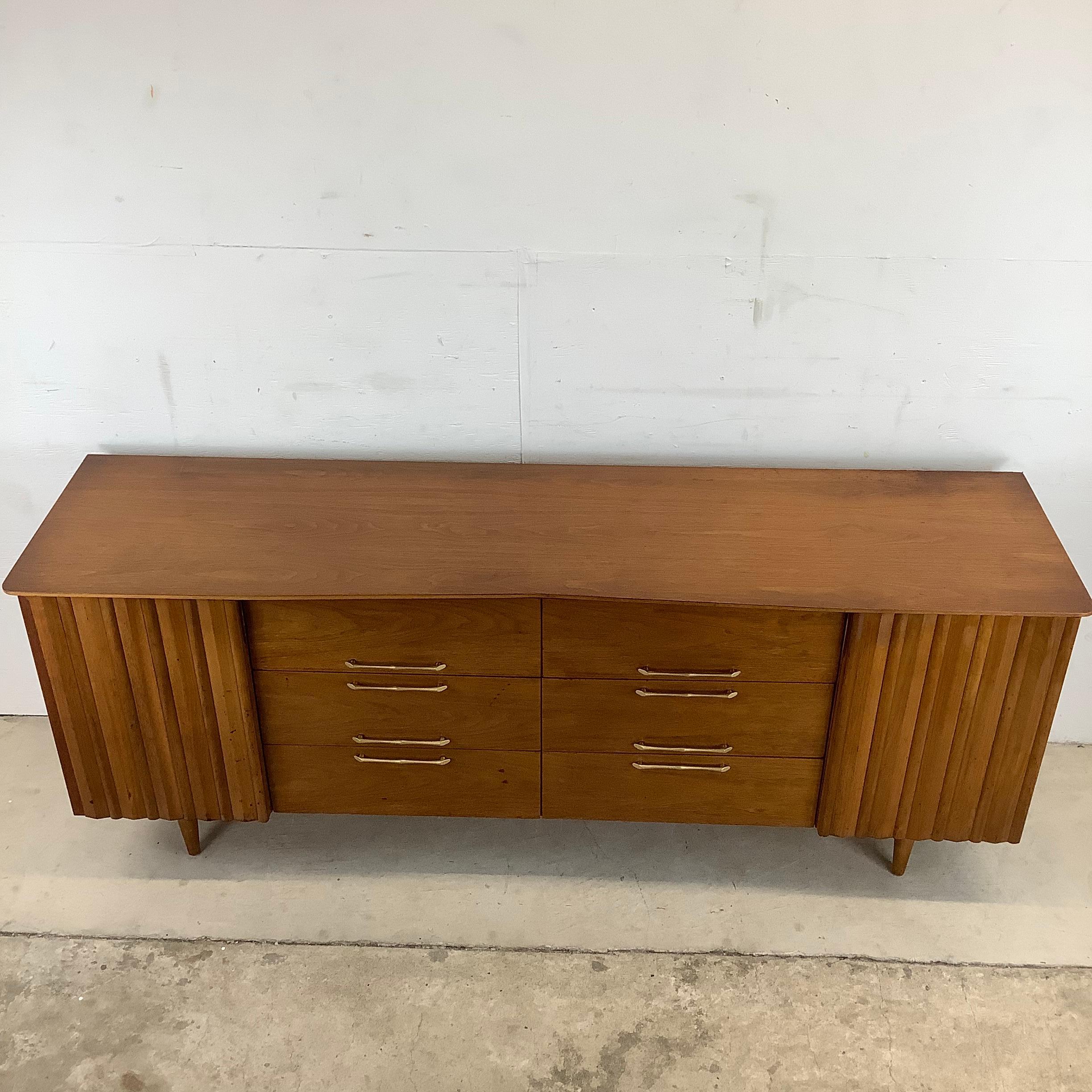 This impressive midcentury bedroom dresser features twelve spacious drawers in a unique danish modern design. The matched vintage wood grain finish and 1960s style make this long dresser an eye-catching centerpiece to any bedroom setting. Original