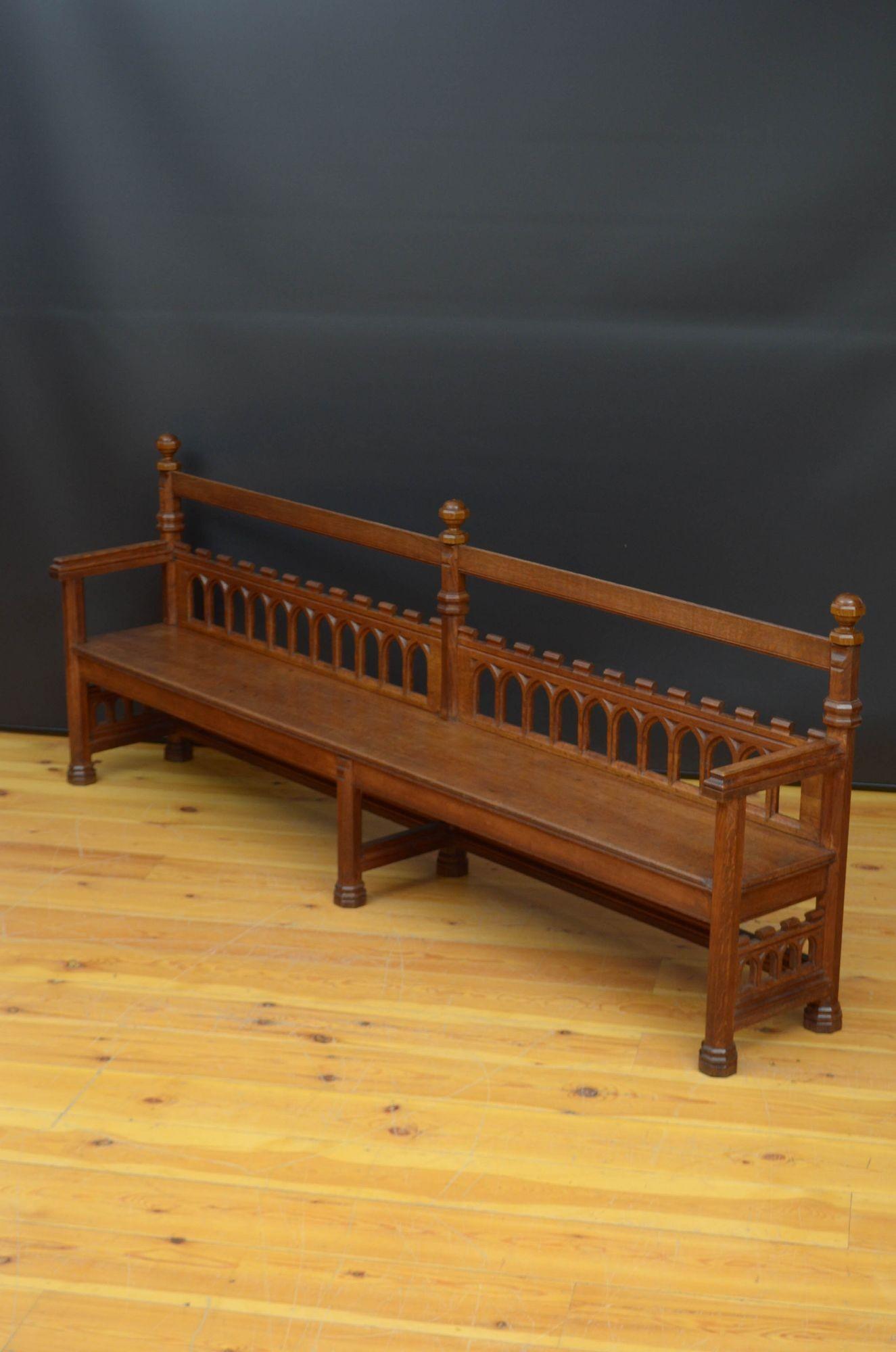 J034 Superb long Gothic Revival hall bench in oak, having shaped top rail with decorative ball finials above arch carved and castellated mid rail, generous solid oak seat with shallow frieze and open, carved arms, all standing on six octagonal