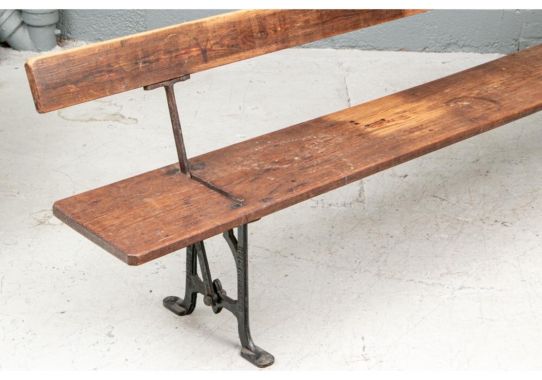 A rustic and very sturdy antique bench from West Bromwich, England. A heavy plank for the back and one for the seat. With black painted shaped cast iron supports on the sides, labeled , “West Bromwich”. The iron is also stamped, “Fisher and Son”.