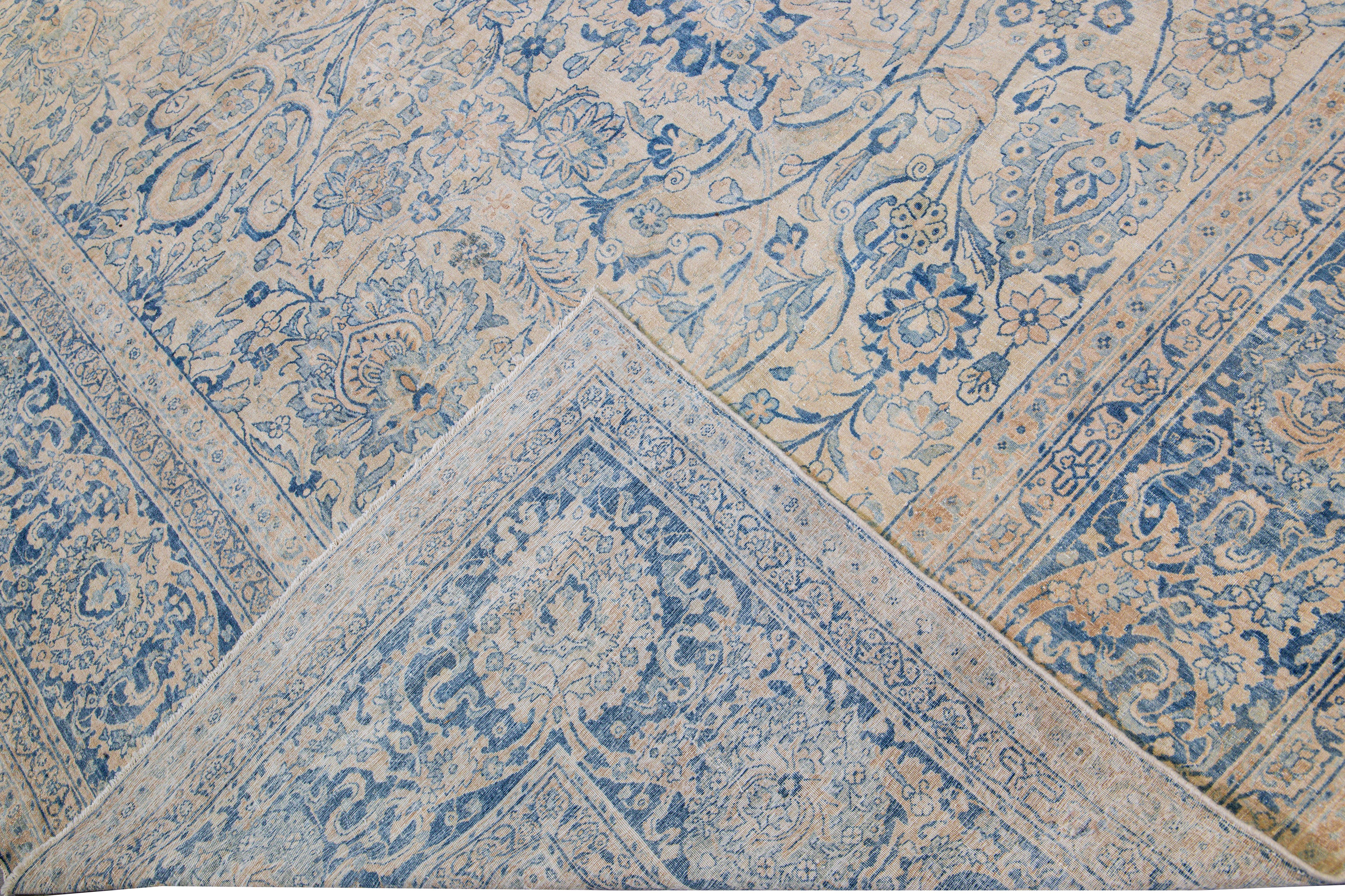 Beautiful antique Oversize Kerman hand-knotted wool rug with a beige field. This Kerman rug has a blue frame and accent that features an all-over botanical pattern design.

This rug measures: 12'7