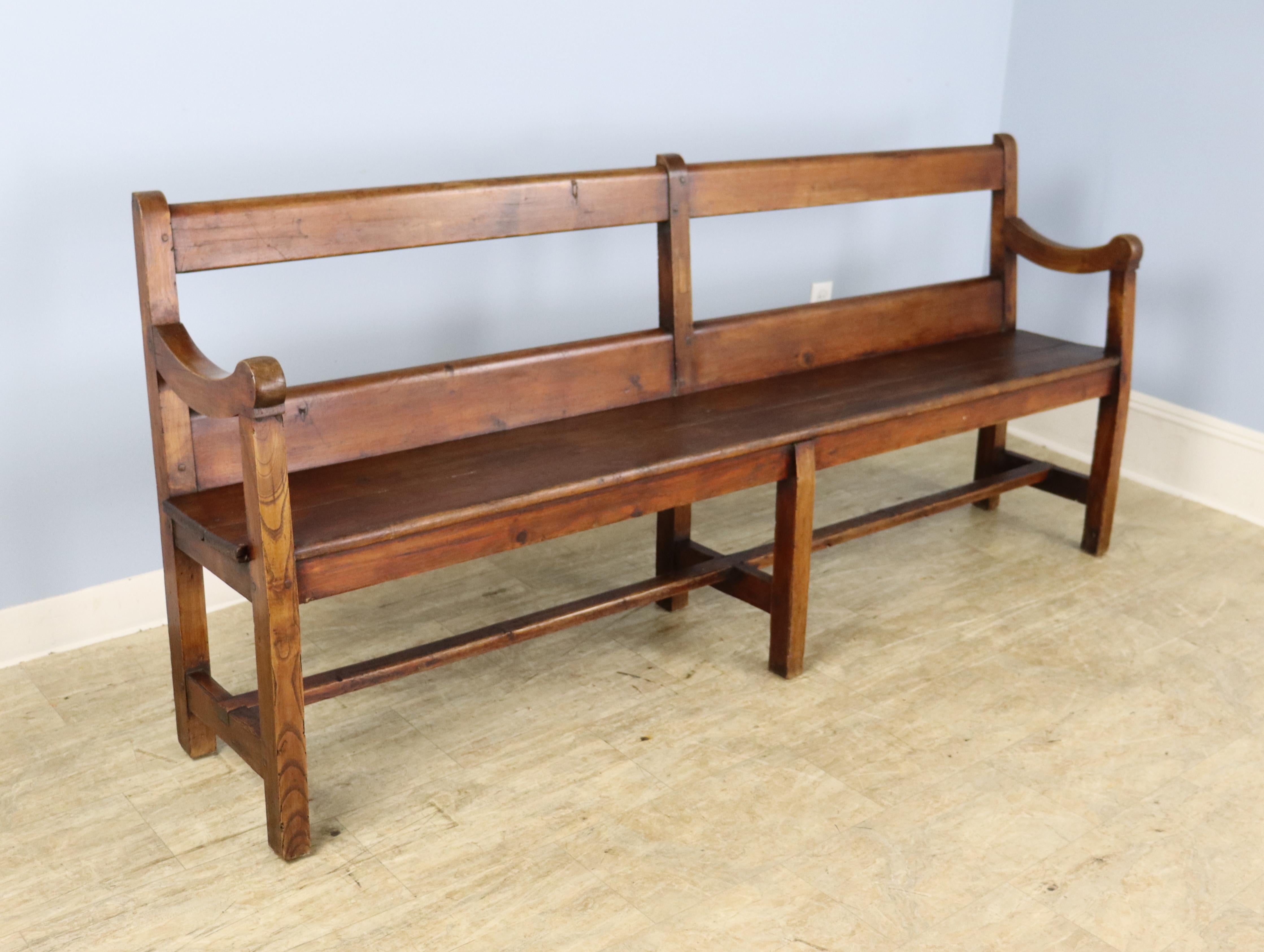 A long bench with a simple silhouette in study pine. Both the color and grain are very good, as is the patina. The profile has a slight recline which makes the piece more comfortable. No wobbles!