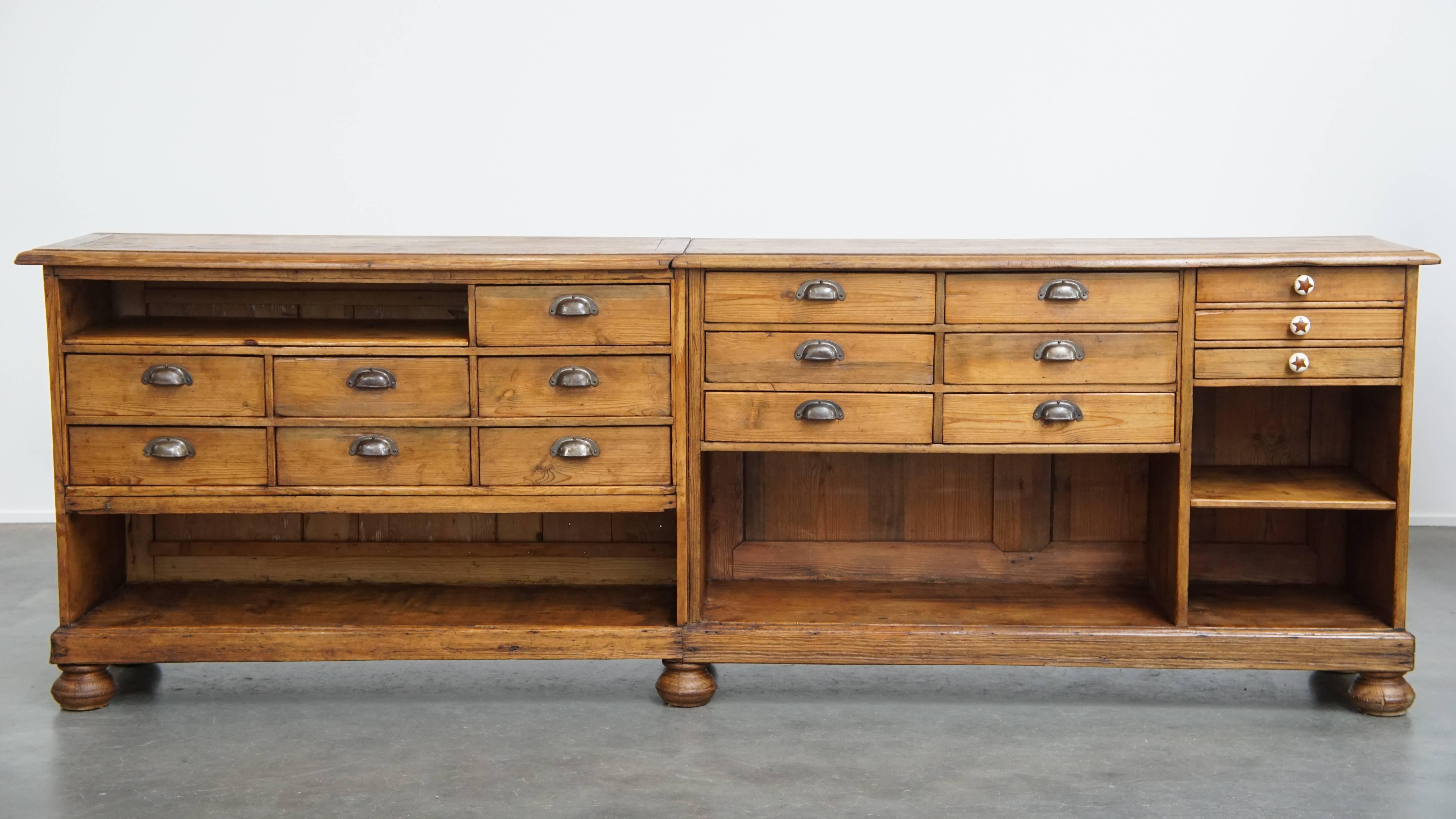 Offered: this long, unique country-style antique pine wood counter / sideboard with turned legs and 16 practical drawers.

This impressive long antique pine wood counter / sideboard is a unique opportunity for true antique lovers! A genuine