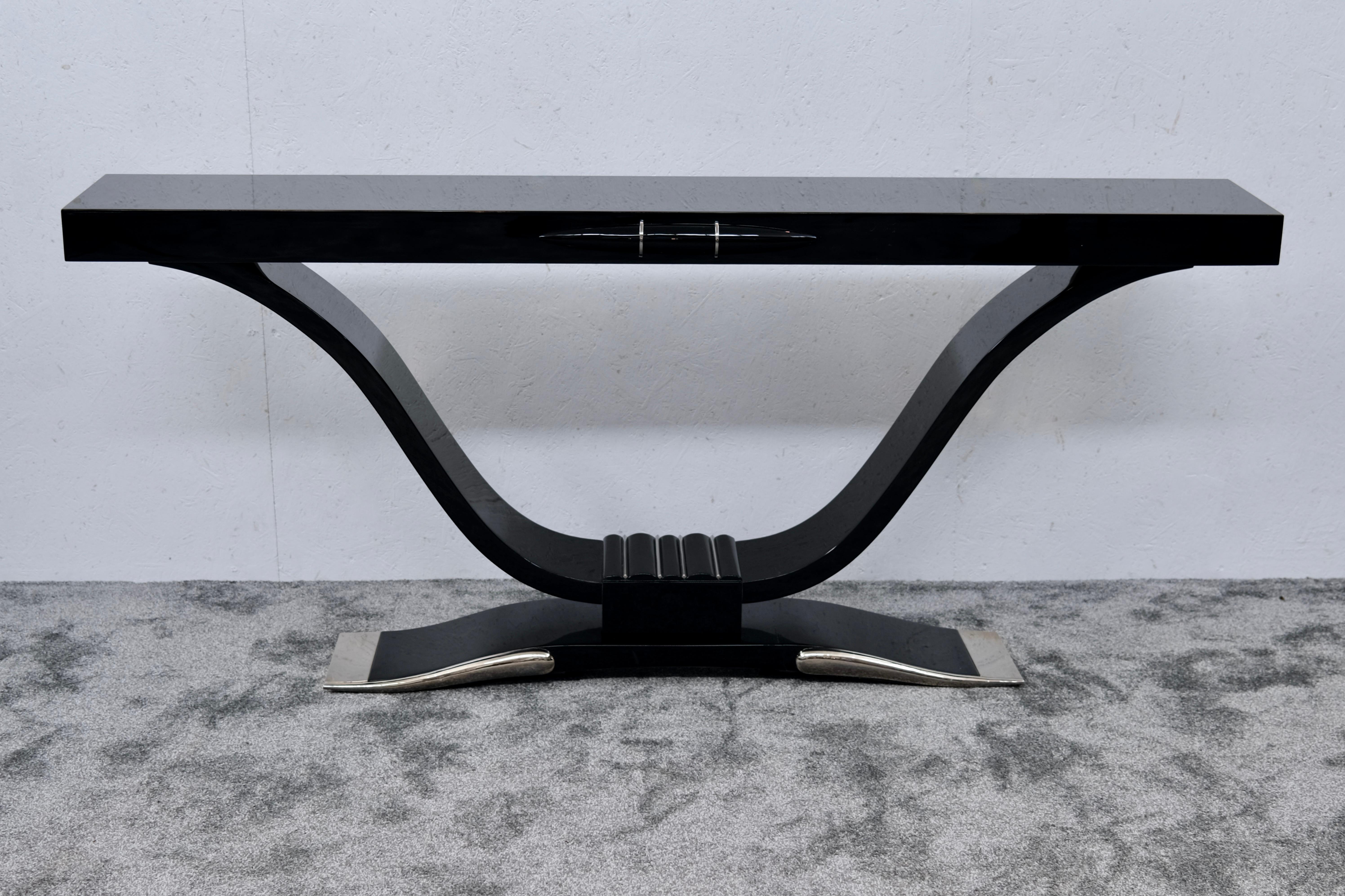 This exceptional Art Deco console table from 1930s France is a celebration of sculptural elegance and period craftsmanship. Finished in a sumptuous high-gloss black lacquer, the piece commands attention with its sleek profile and dramatic form.

The