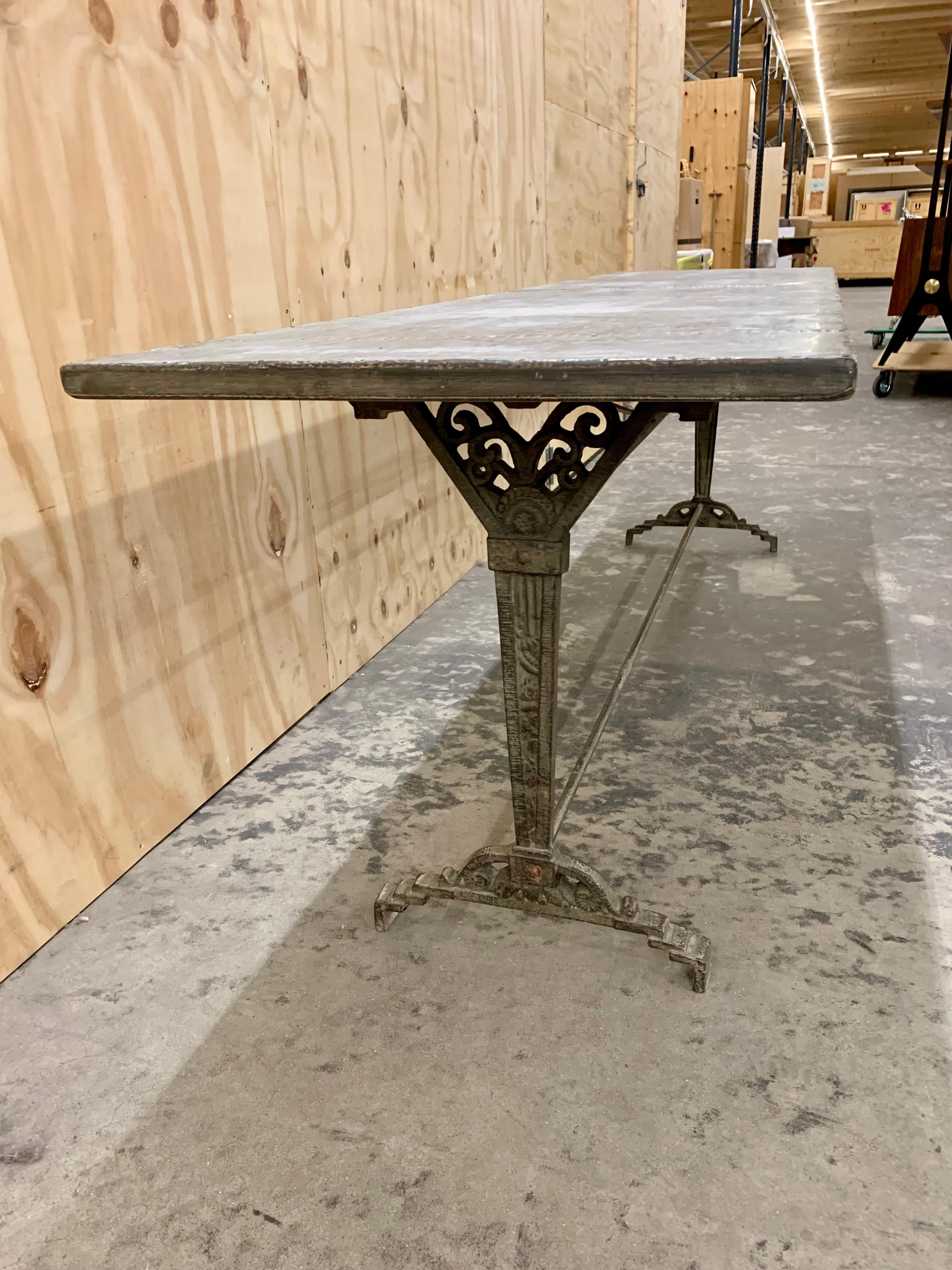 Beautiful and rare French antique Art Deco bistro table with a decorative cast iron base and a nitted metal table top. The table is unusually long and makes a fantastic dining table that can fit 8 people around it.
