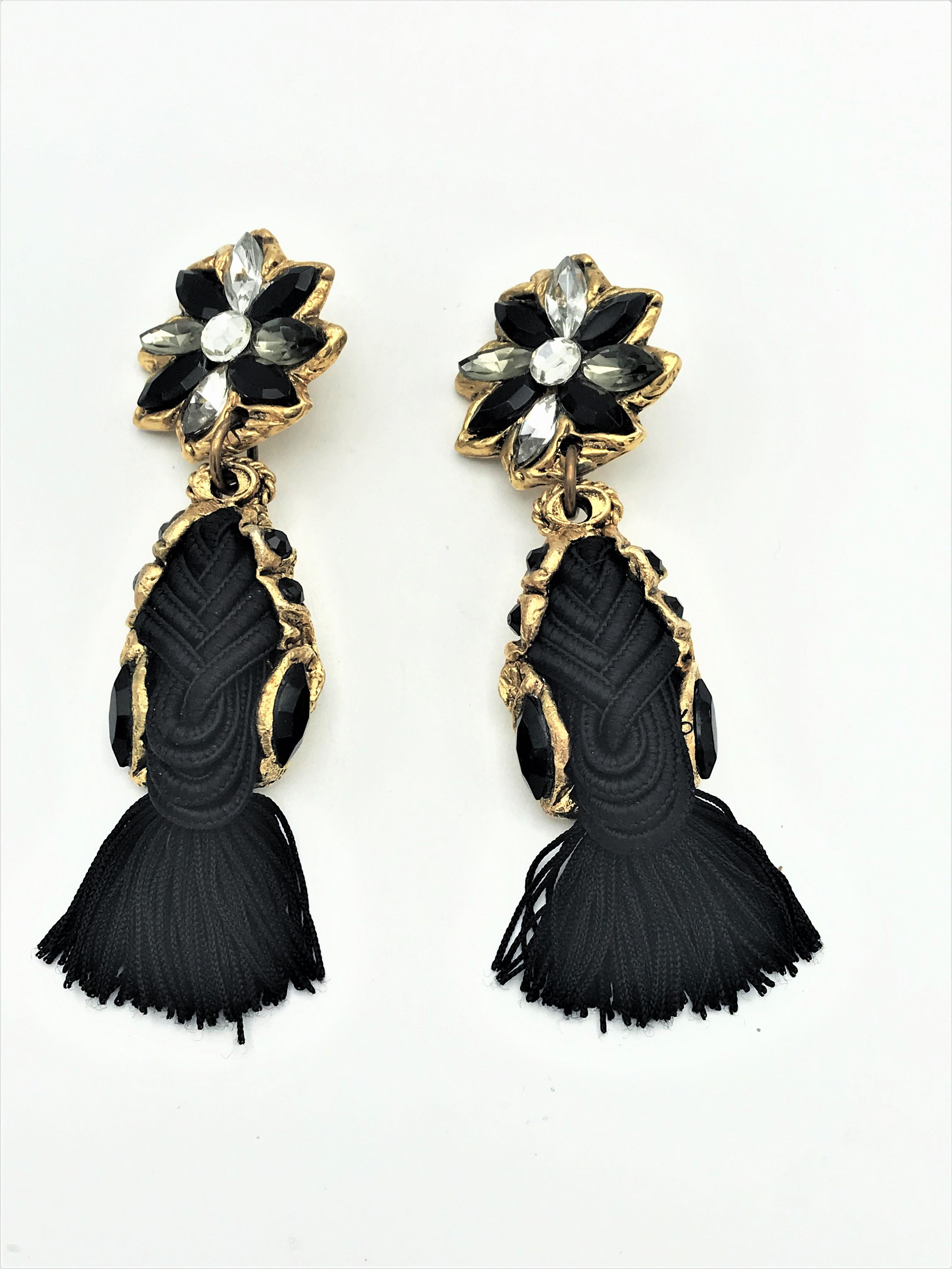 Very decorative long black ear clips made of gold colored resin and fine black trimmings cord. The upper part is a star with black and clear rhinestones. A very individual and beautifully crafted clip.
Dimensions: Whole length 12 cm. Star 4 cm in