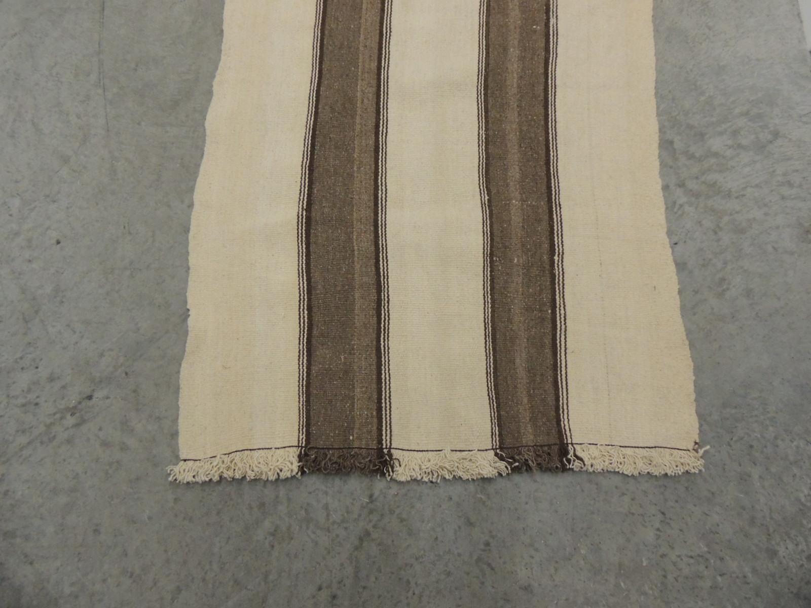Long brown and natural Berber hallway or stairs runner.
Striped Kilim flat-weave rug/runner with small end fringes.
Comes with runner pad.
Size: 30.5