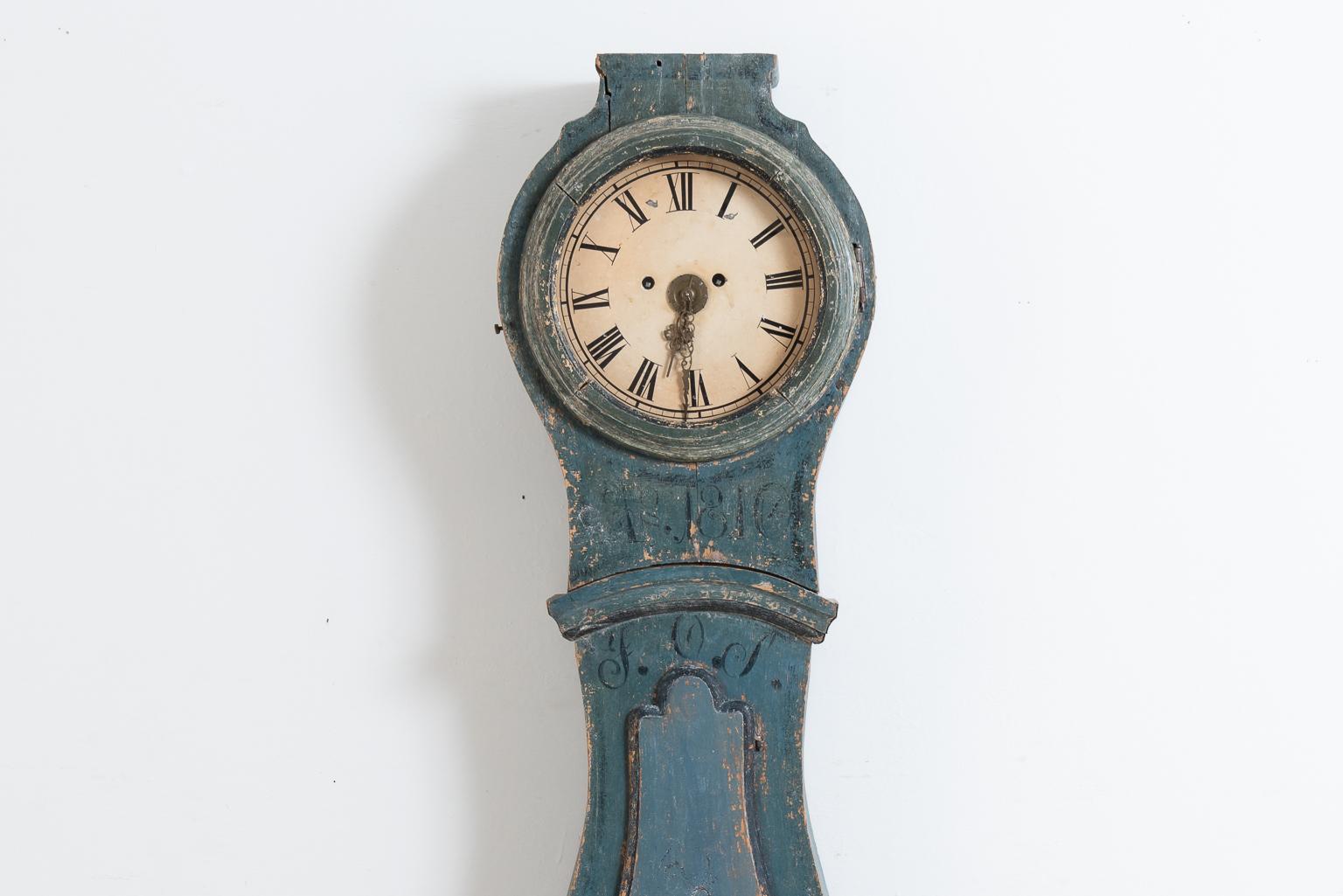Long case clock from northern Sweden. The clock is in original untouched condition and is painted with the blue original paint. The skirt is decorated with painted flowers and there's traces of a monogram as well as a dating. The hood has a minor