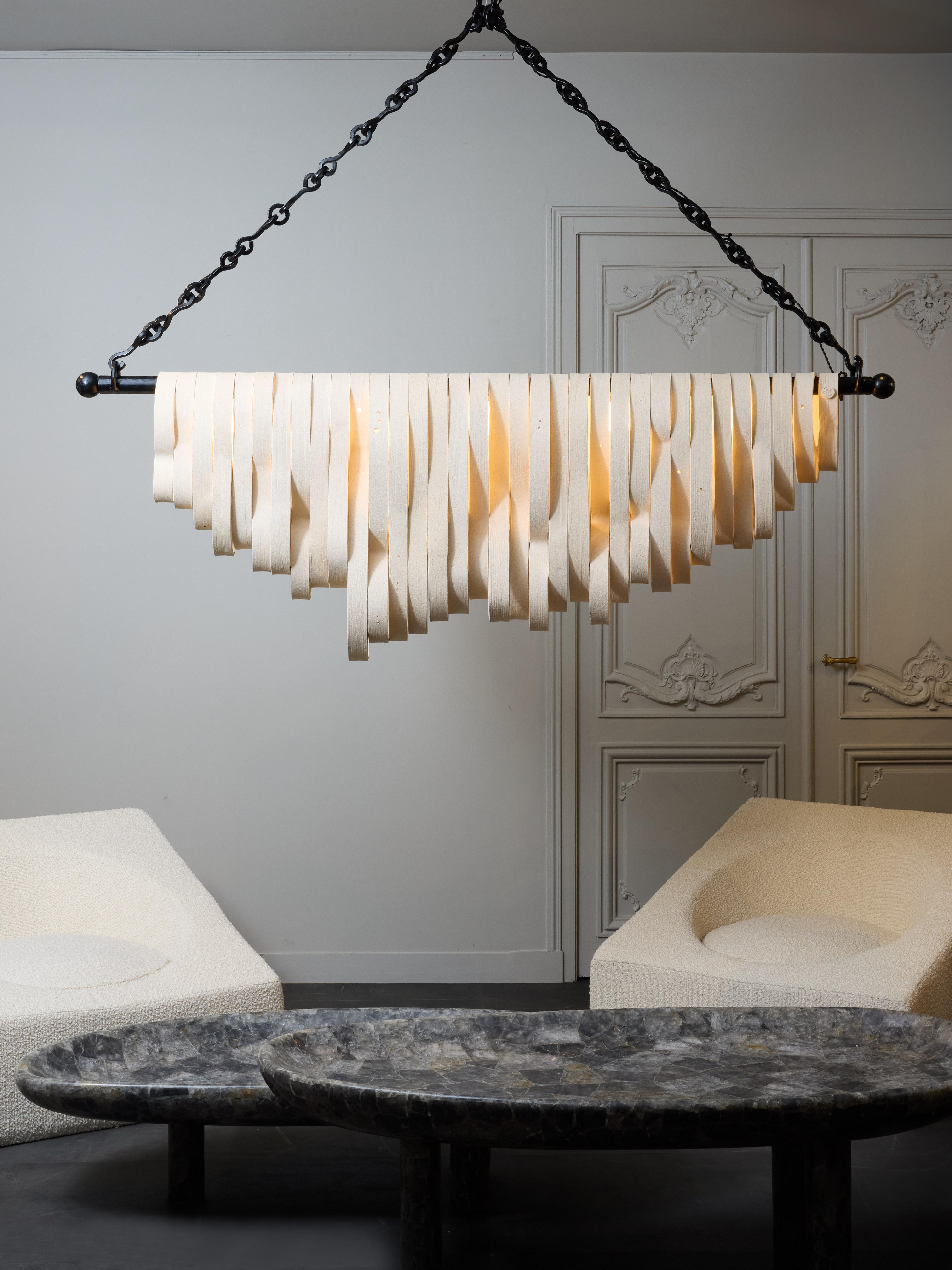 Beautiful new design by the french artist Olivia Cognet, this chandelier made of a central iron horizontal stem holding the sources of light (G9 sockets encased in small opaline globes) and supporting more than thirty handmade ceramic free shaped