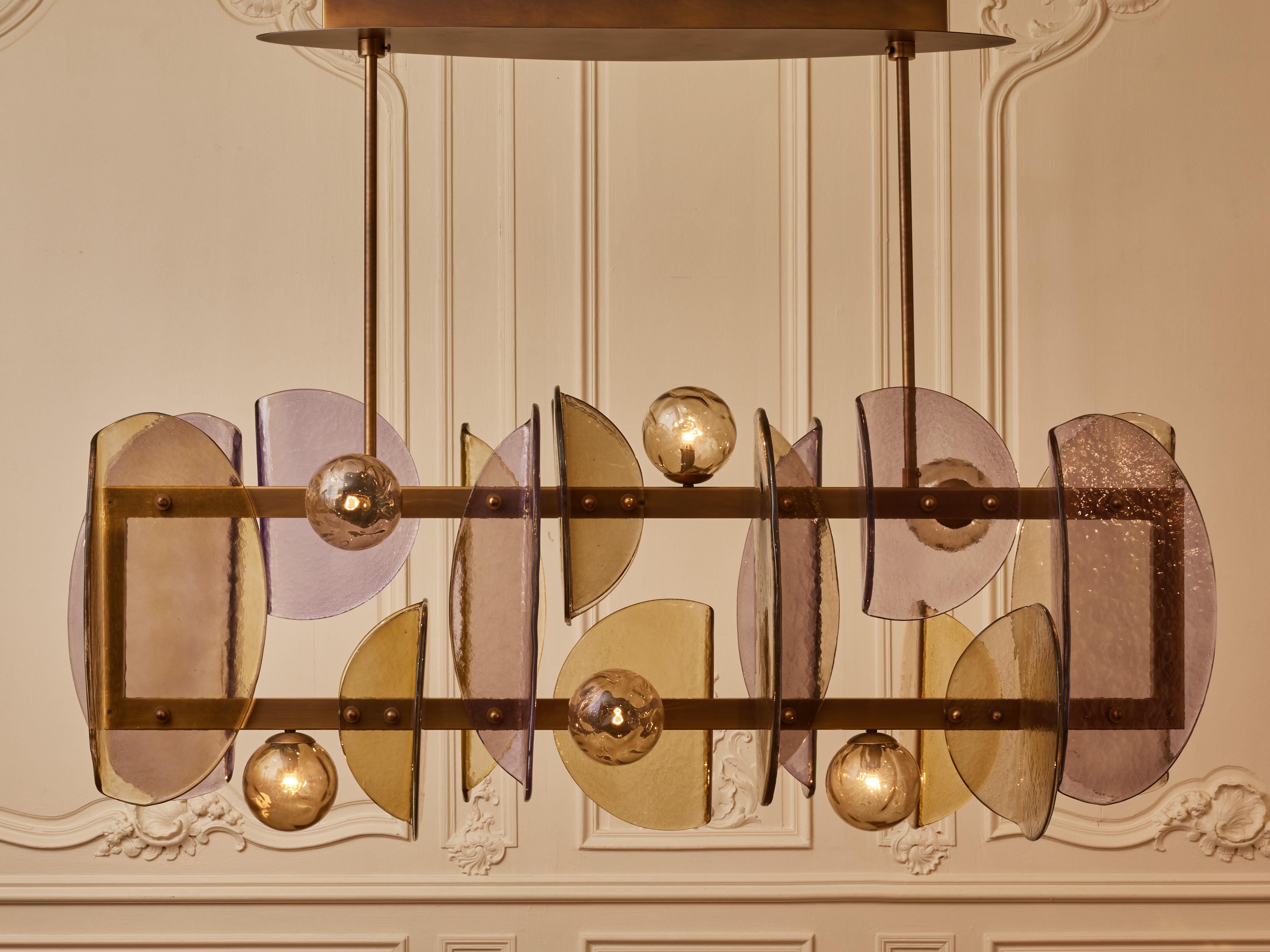 Long chandelier in patinated brass with globes and plates in Murano glass.
Creation by Studio Glustin.