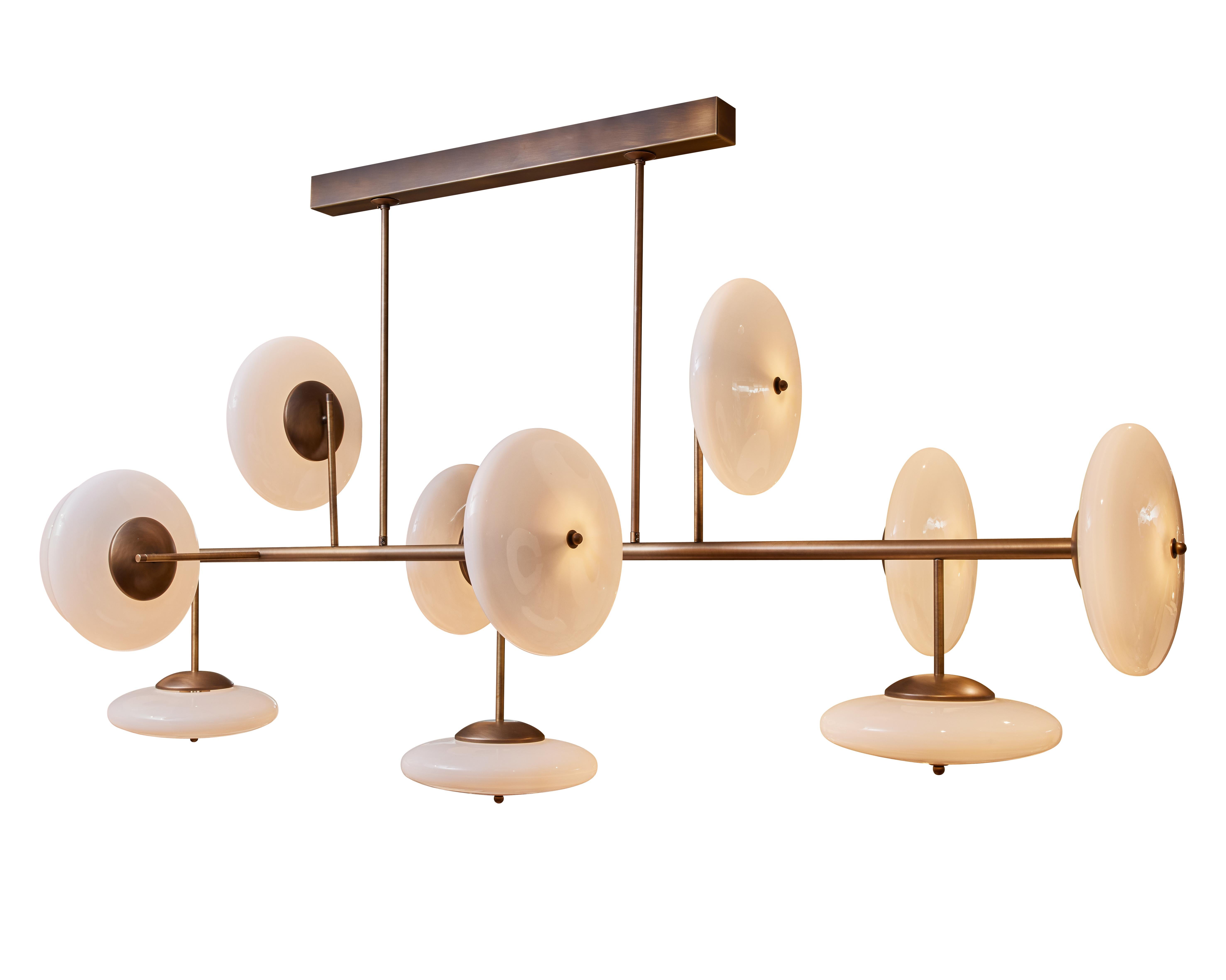 Lampadario lungo in ottone patinato e vetro opalino.
Creazione dello Studio Glustin.
 