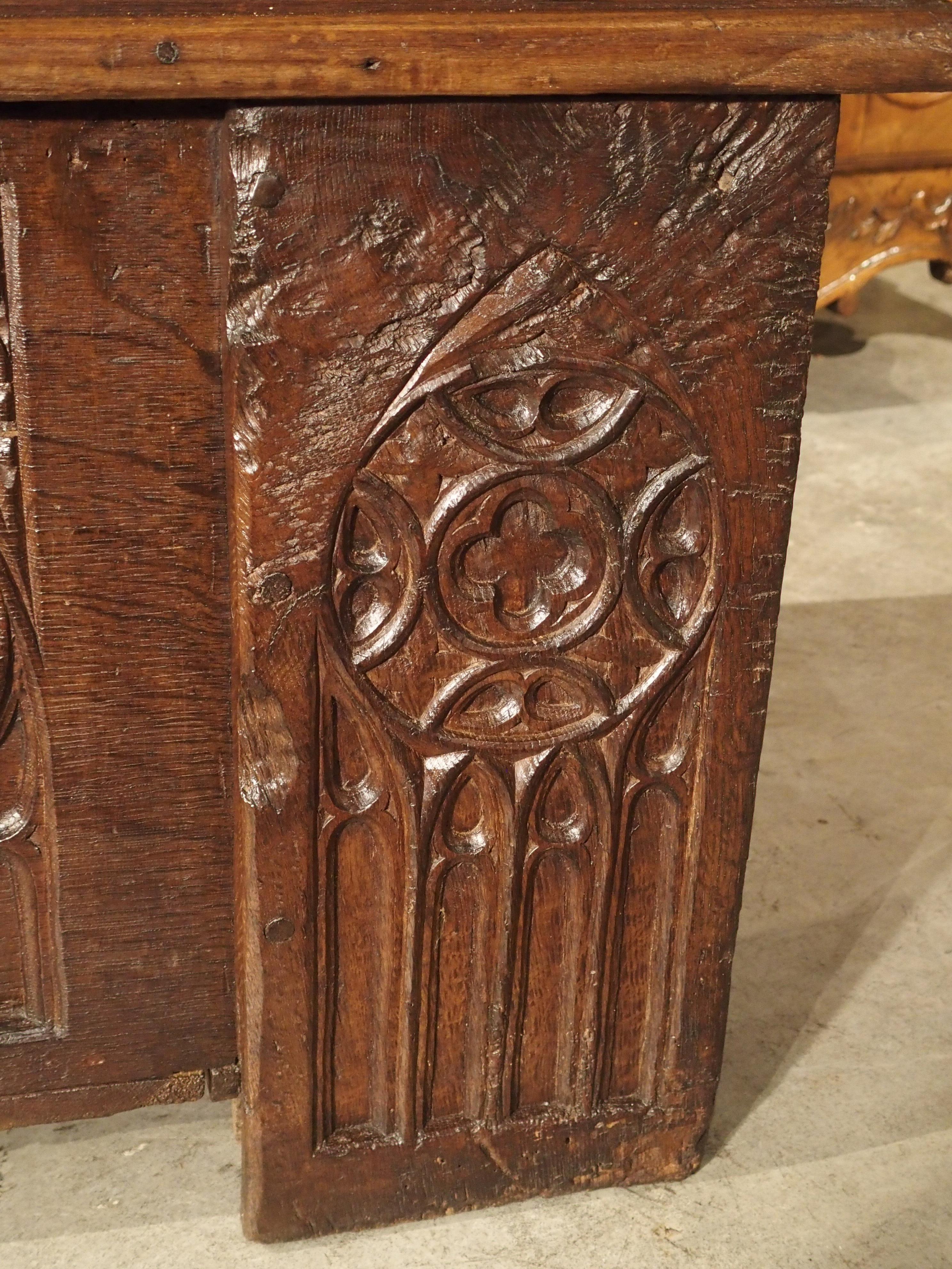 This is an unusually long Gothic style trunk from France, measuring nearly 6.5 feet long. It is carved from thick oak planks, and it dates to circa 1800. The trunk has well carved characteristic Gothic ornamentation on all of the front panels, while
