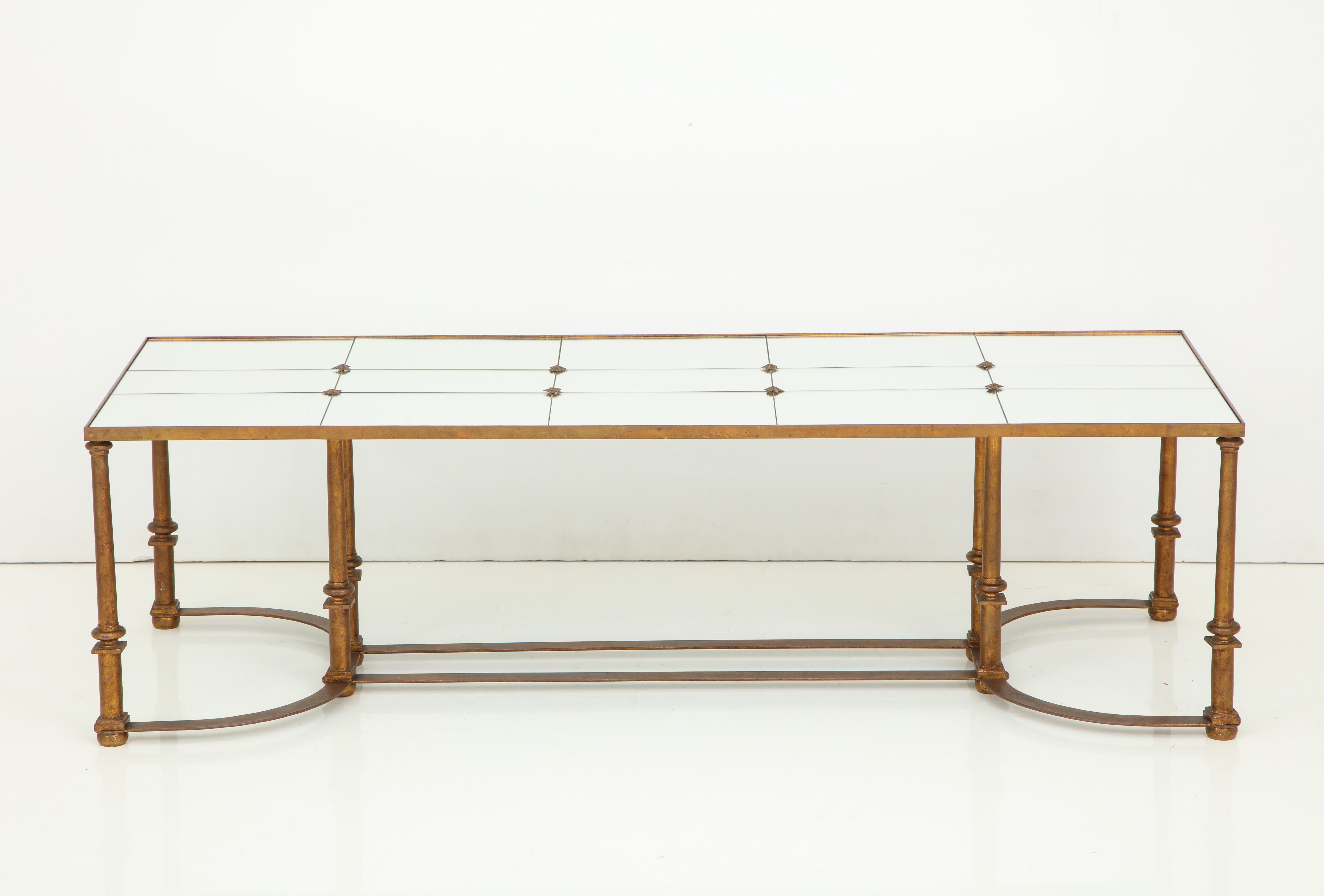 Neoclassical gilt metal coffee table, inset with fifteen mirrored glass panels and raised on round legs, joined by bowed stretcher.
