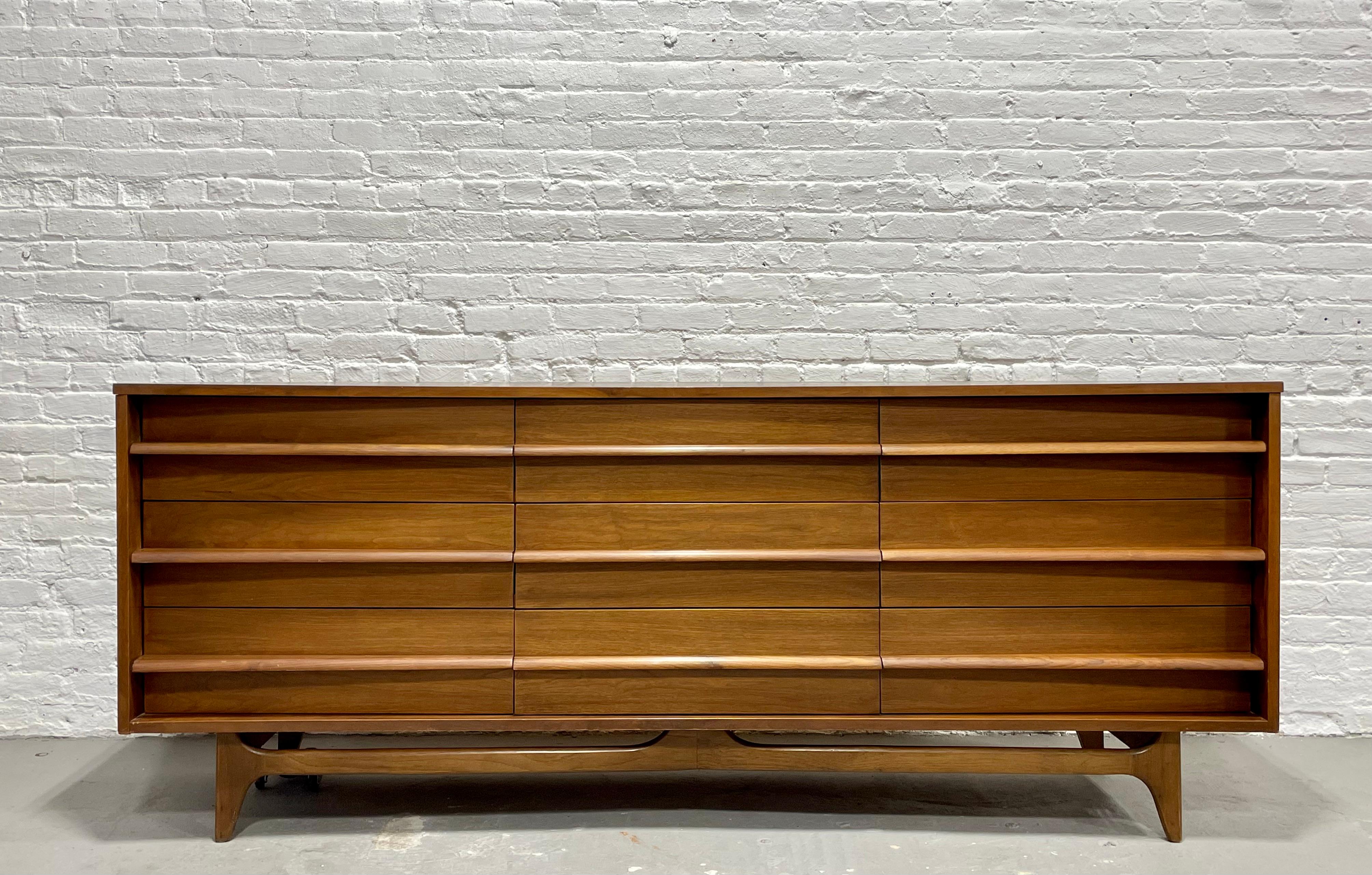 Long Walnut Mid-Century Modern Dresser / Credenza with fabulous concave facade, sculpted pulls and newly refinished tabletop. This unique long dresser offers loads of storage space - a total of NINE deep and spacious drawers running smoothly with