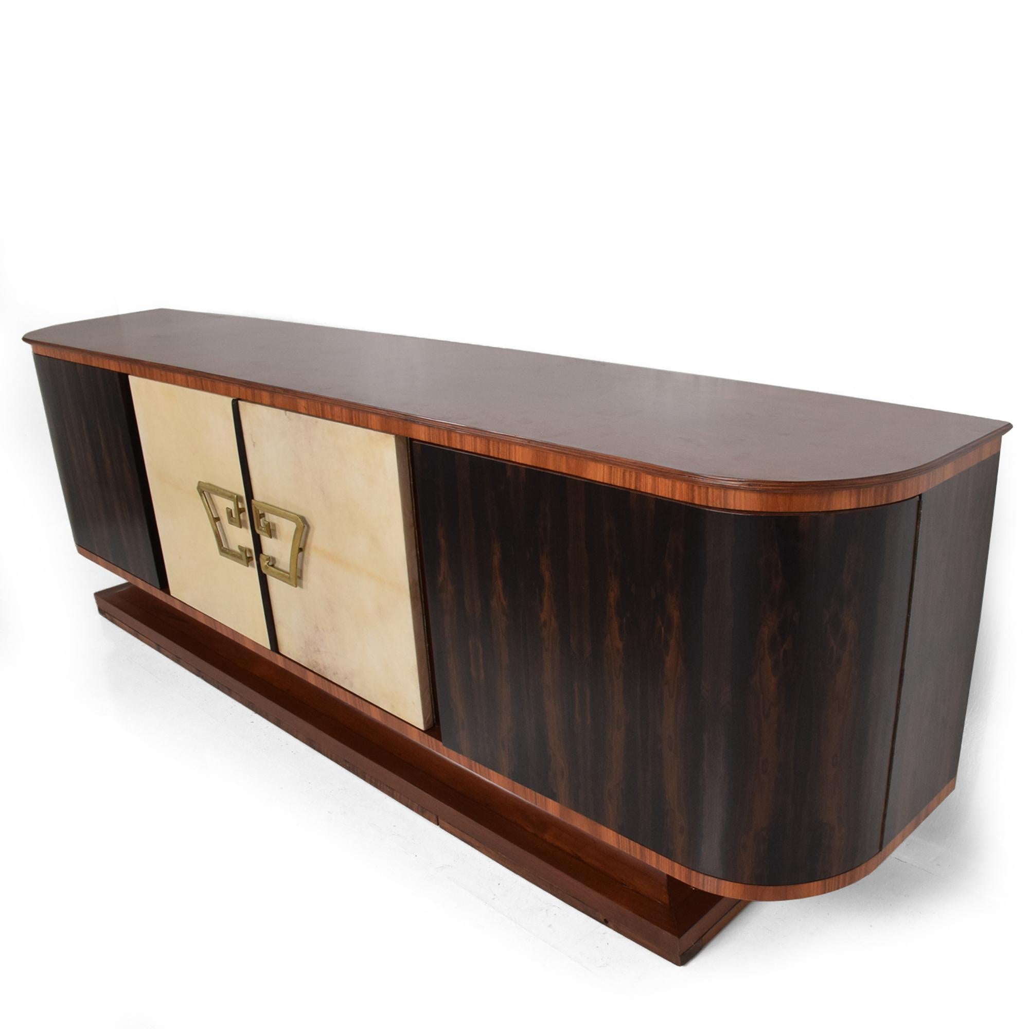 Mexican Modernism glamorous Hollywood Regency long curvy credenza in exotic wood, goatskin, mahogany and rosewood.
Center doors are covered in goatskin Leather with sensational solid brass pull handles.
Center section features eight pull out