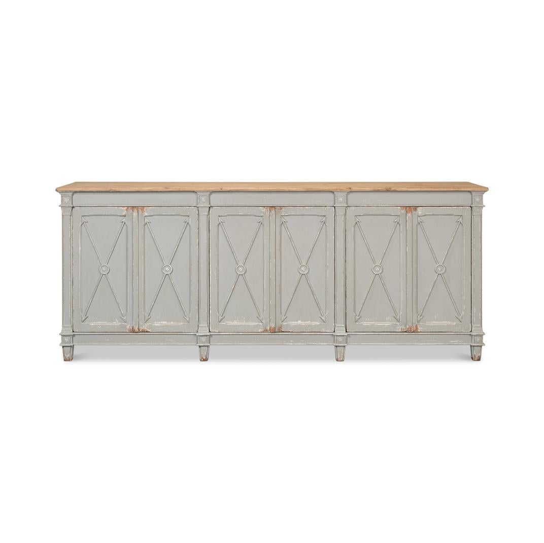 This piece features a hand-rubbed and distressed muted gray-painted finish and a natural finished top, complementing its six doors adorned with a classic cross-arrow design. Crafted from high-quality pine, this buffet offers a rustic, antiqued