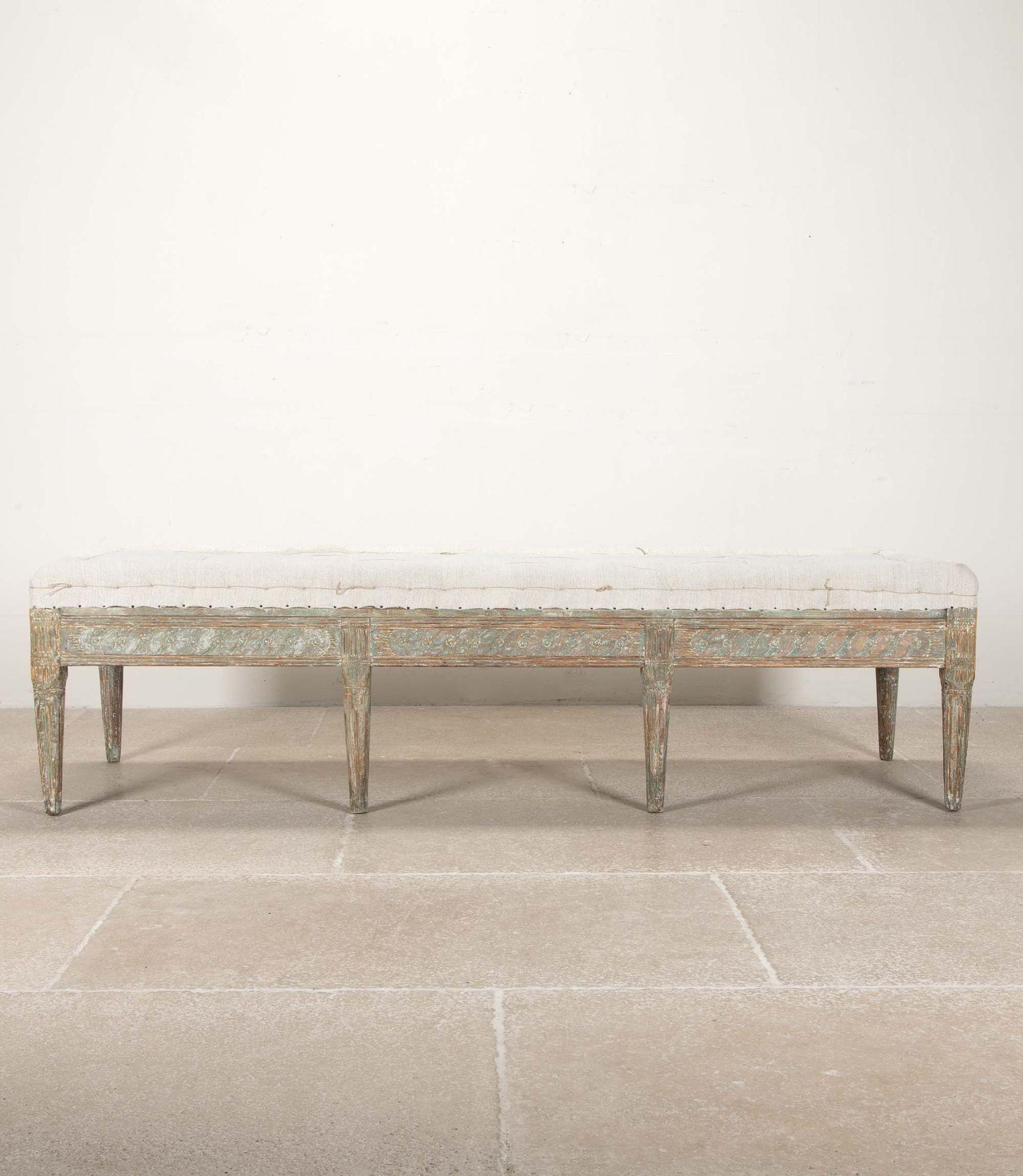Sgabello o panca svedese lunga dell'inizio del XIX secolo con dettagli intagliati a mano sulla parte anteriore e su entrambe le estremità. 

Tracce di vernice originale grigio verde tenue.

Con il tradizionale rivestimento in lino antico svedese