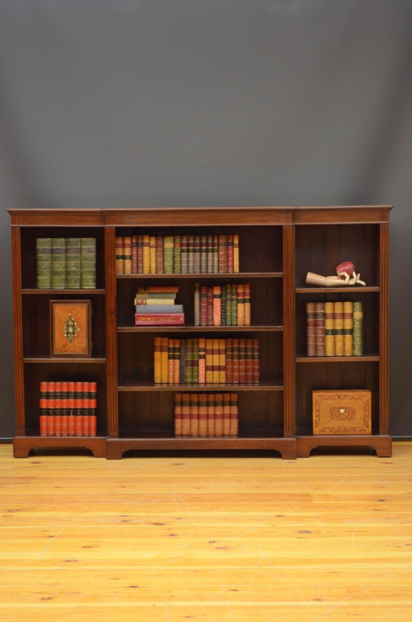 St023 Edwardian breakfronted open bookcase in mahogany, having oversailing moulded top above a shallow frieze and projecting centre section with three height adjustable shelves, flanked by reeded pilaster and further open sections with two height