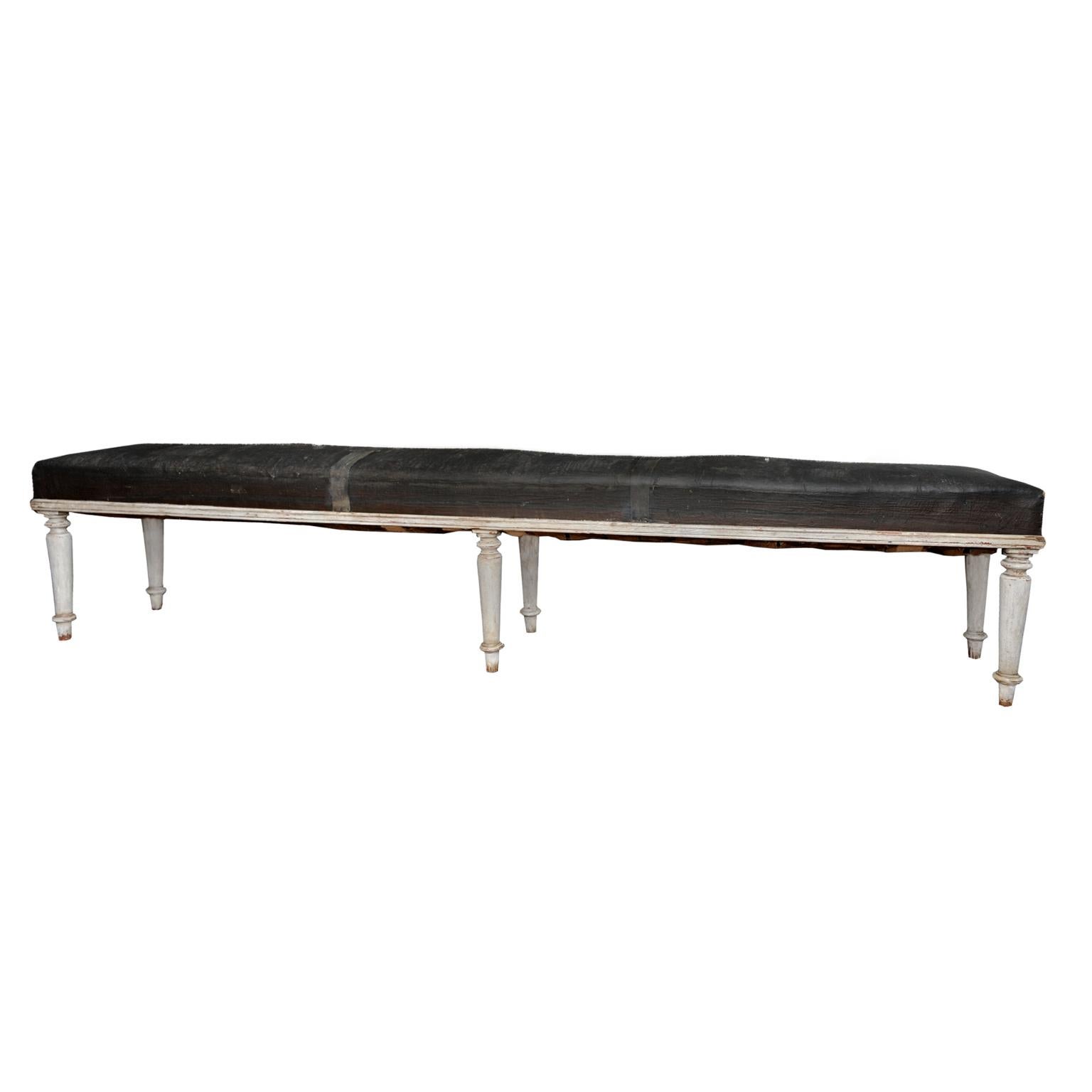 This is a very attractive and unusually long (8ft/245cm) English George IV painted hall or gallery bench, retaining its original leather cloth covering, circa 1825.