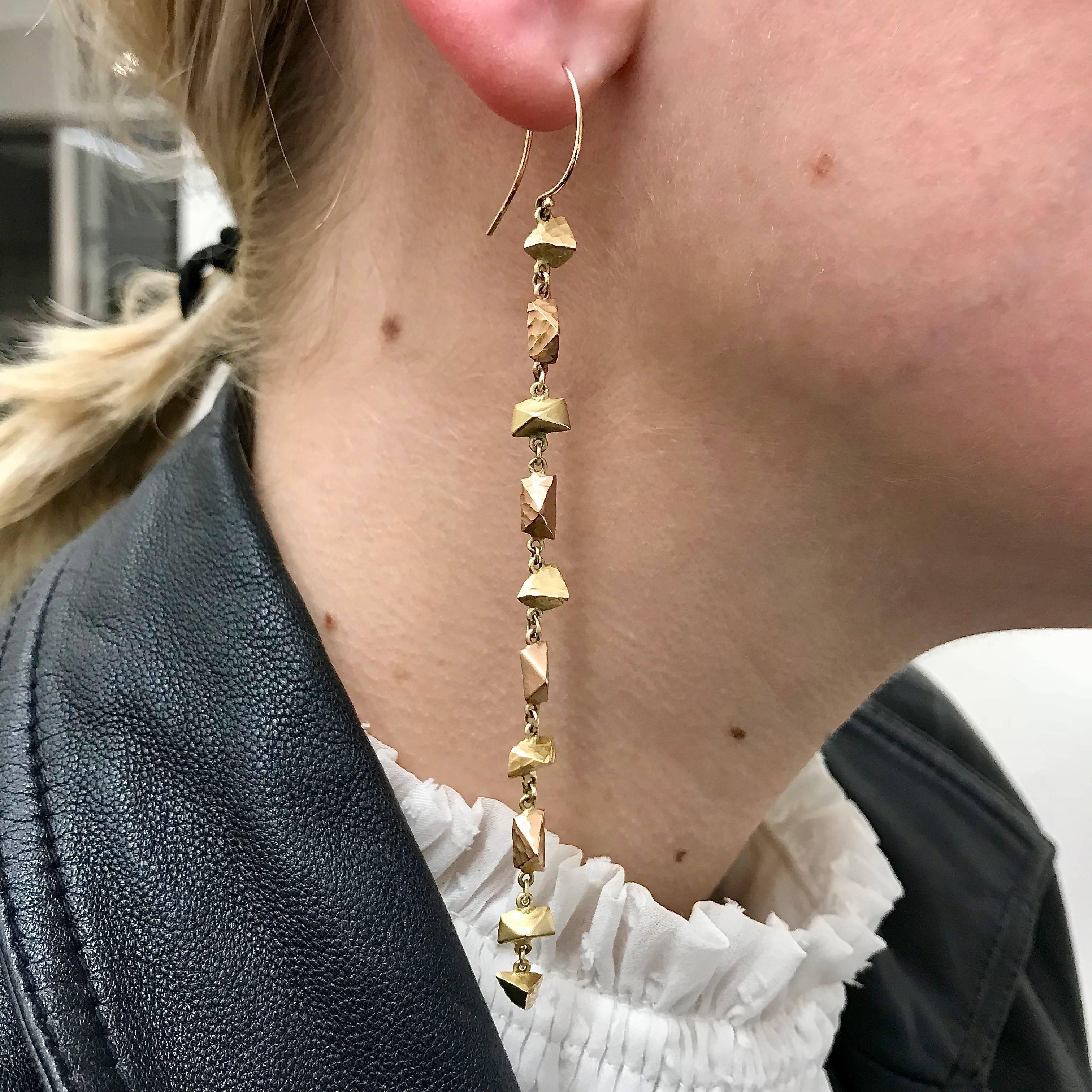 Droplets of hand-carved eighteen karat gold in the form of asymmetrical pyramids and triangles cascade from an ear wire. A mix of rose and yellow gold compose the earrings in a subtle asymmetry that dangles to dust the wearer's shoulder. Each of the