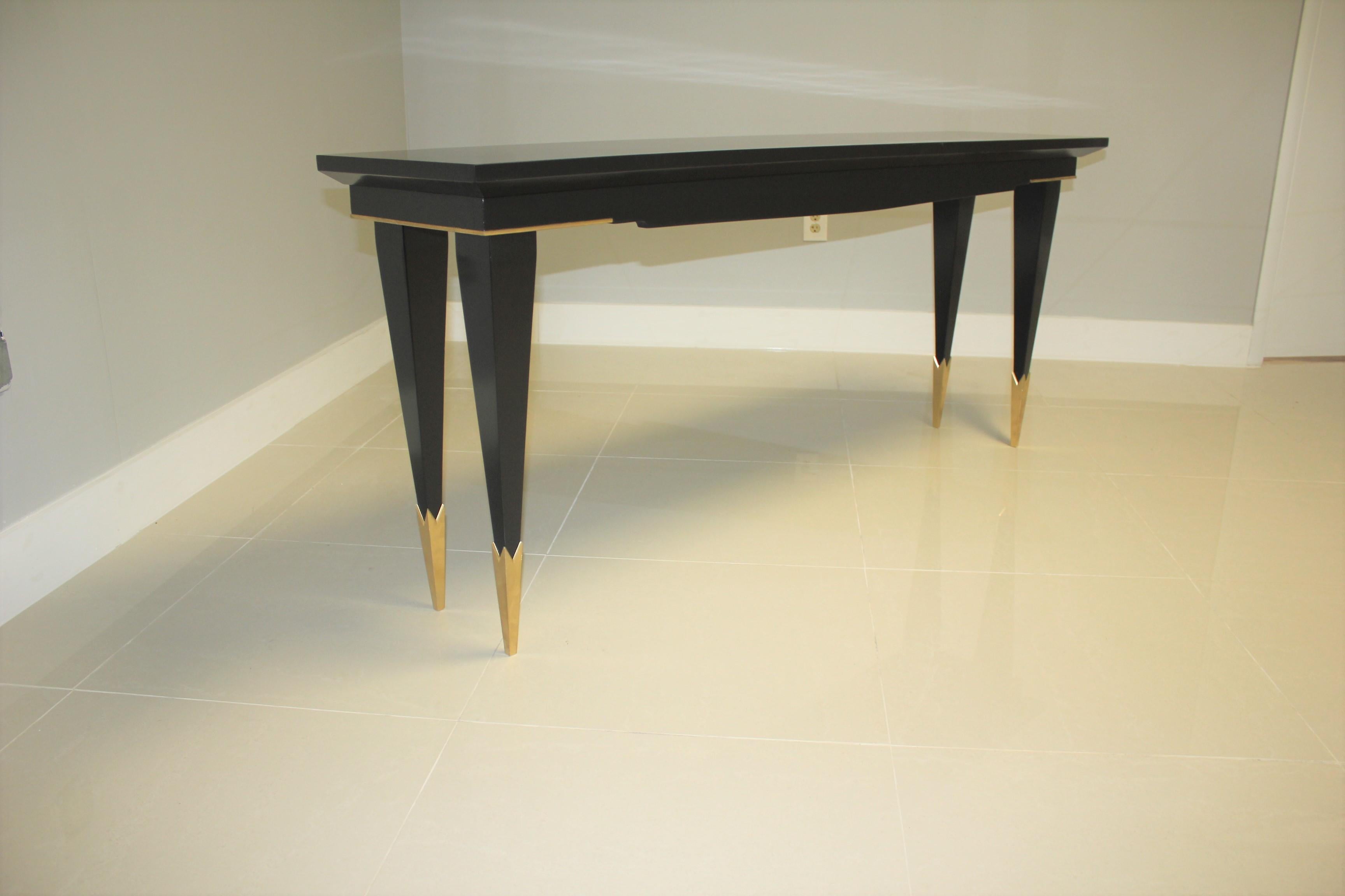 A beautiful long French Art Deco Style console table, circa 1940s. The mahogany wood has been ebonized and finished with a French polished high luster, the back of console table are finish too, the legs have brass toe caps, with beautiful brass