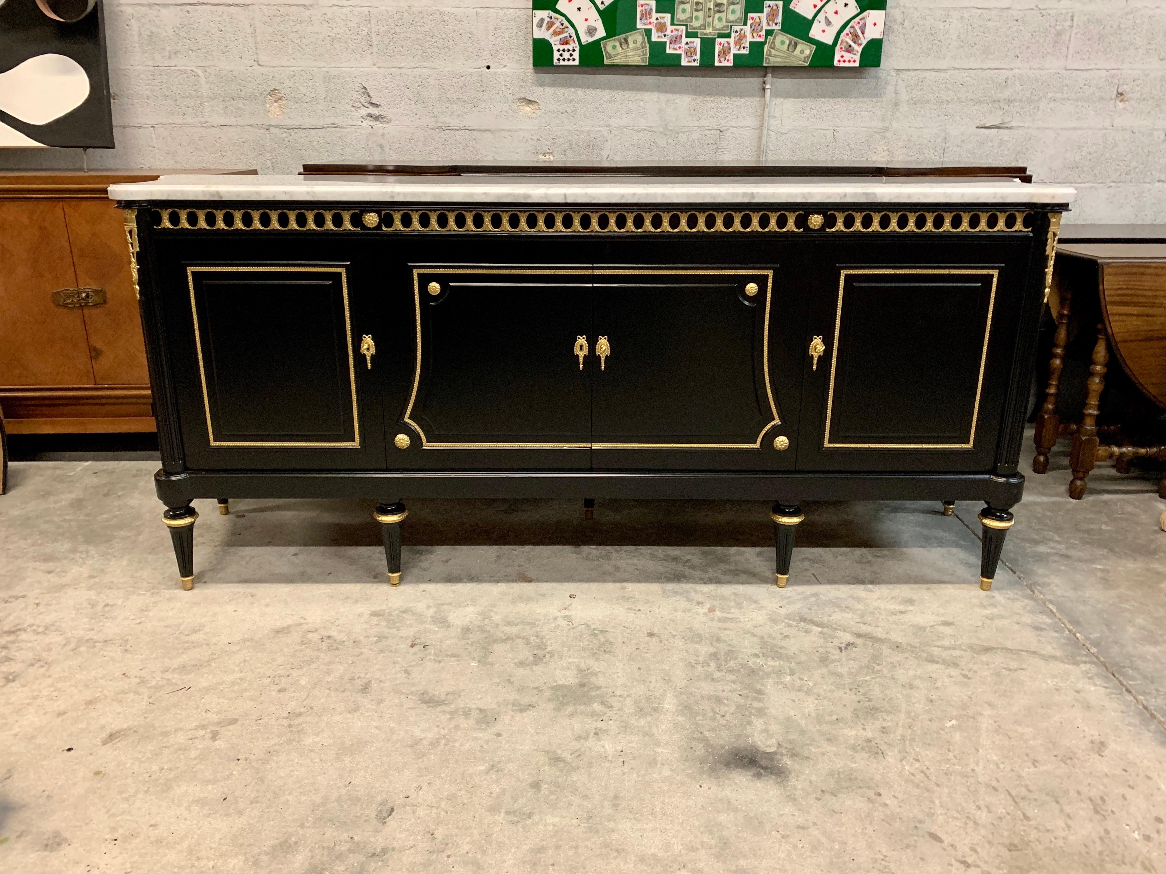 Long French antique Louis XVI style sideboard or buffet made of mahogany with a beautiful Carrara marble top, the mahogany wood has been ebonized and finished with a French polished high luster inside and outside, The buffet has 4 doors and 4