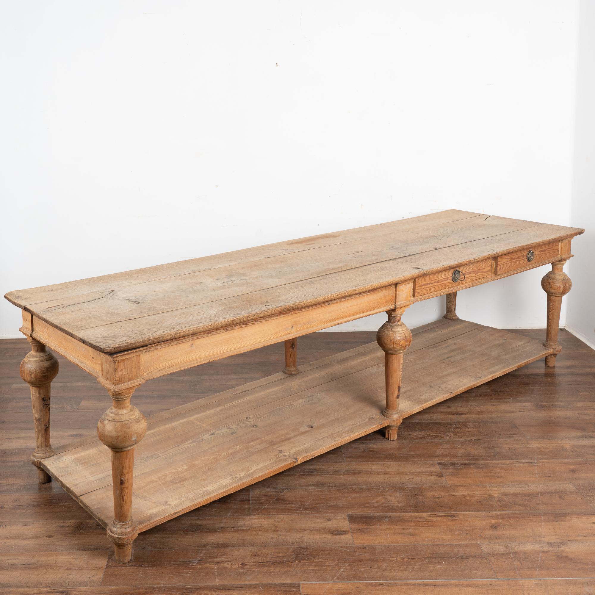 Impressive in size at over 9' long, this French oak drapers table is visually stunning with its six turned legs, two drawers and a lower shelf.
Three planks comprise the top with generations of use seen in every crack, stain and separation of the