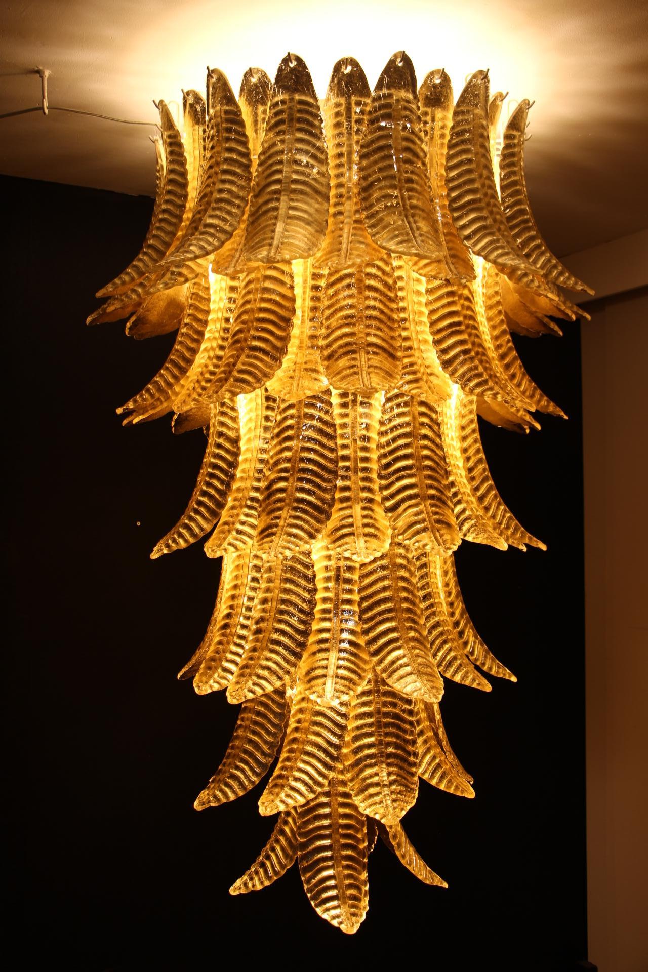 This spectacular long chandelier was entirely handcrafted in Murano. Each single leaf was individually made in high quality blown glass, this is why we can notice very light difference from a piece to another. Its gold color was made thanks to 24
