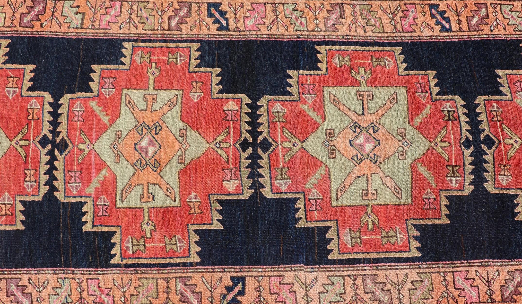 This antique Persian Azerbaijan styled runner has been hand-knotted in wool. The rug features a sub-geometric medallion design, and is enclosed within a complementary, multi-tiered border. Rendered in multicolor, the rug has been made into a great