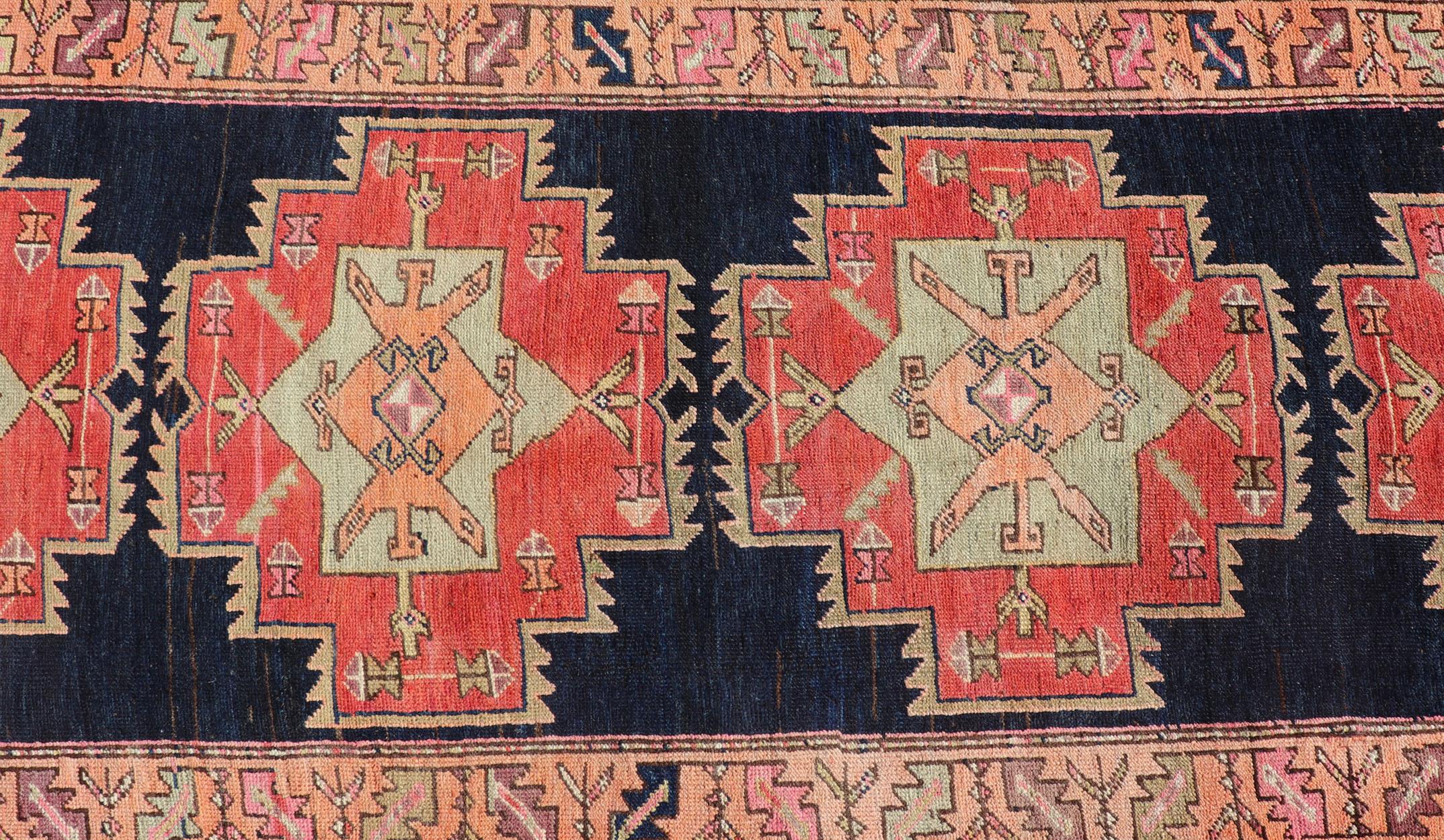 Cet ancien tapis persan de style azerbaïdjanais a été noué à la main en laine. Le tapis présente un motif de médaillon sub-géométrique et est entouré d'une bordure complémentaire à plusieurs niveaux. Rendu en multicolore, ce tapis s'adapte à une