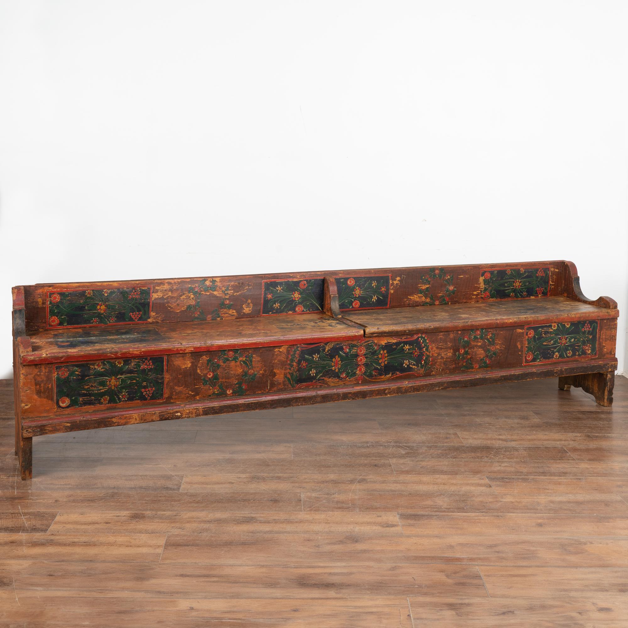 Antique hand painted bench with divided storage at just under 10' long .
Traditional Eastern European folk art painting with brick red/brown background and dark blue painted panels with red, green and yellow florals.
Two bench seats open to reveal