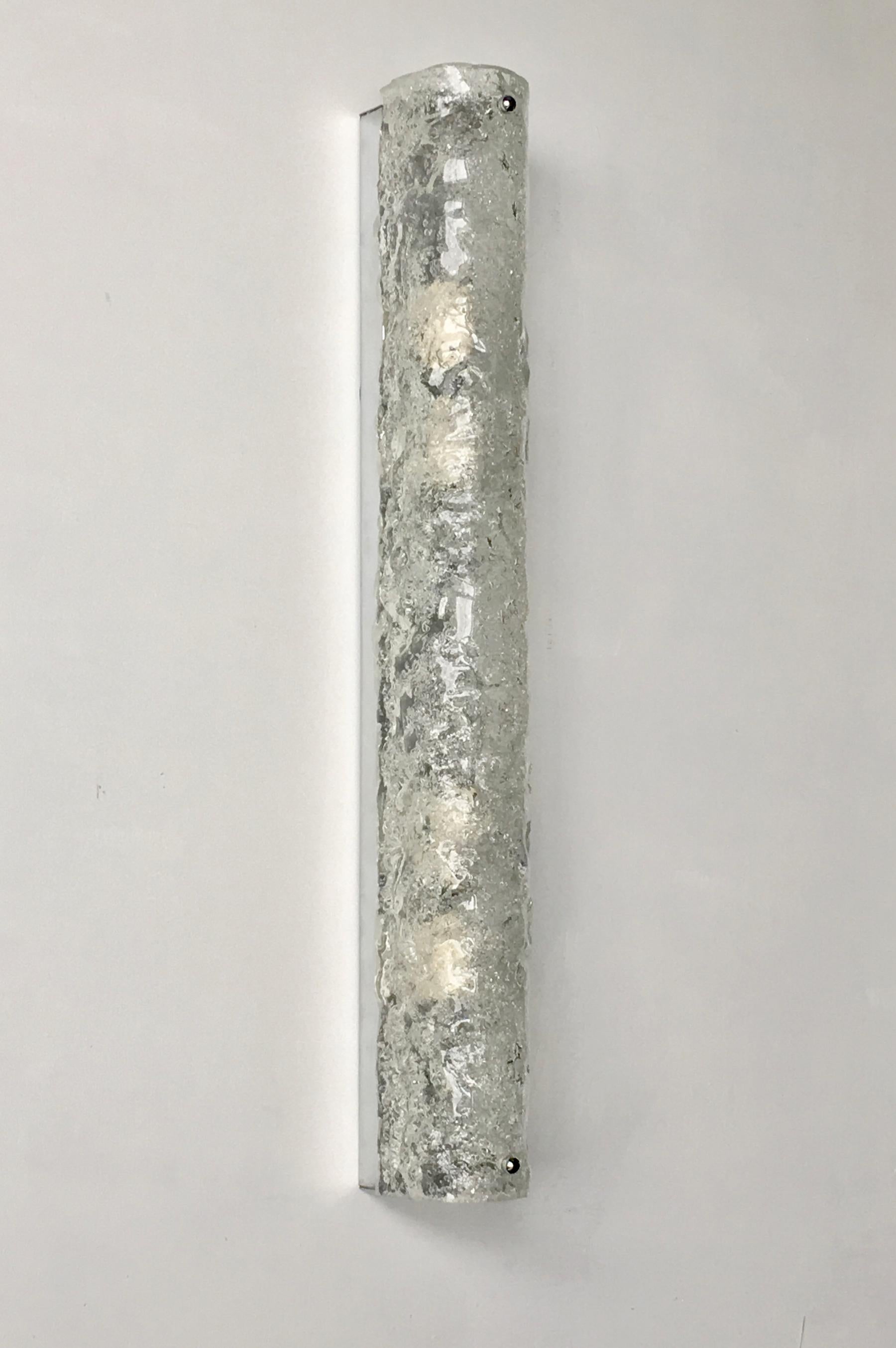 Long, slim ice glass sconce by Hillebrand, Germany, 1960s. 

Curved glass shade of bubbled and textured glass over chrome back plate; the glass is held in place by chrome screws. The piece is in good original condition with minor signs of wear in