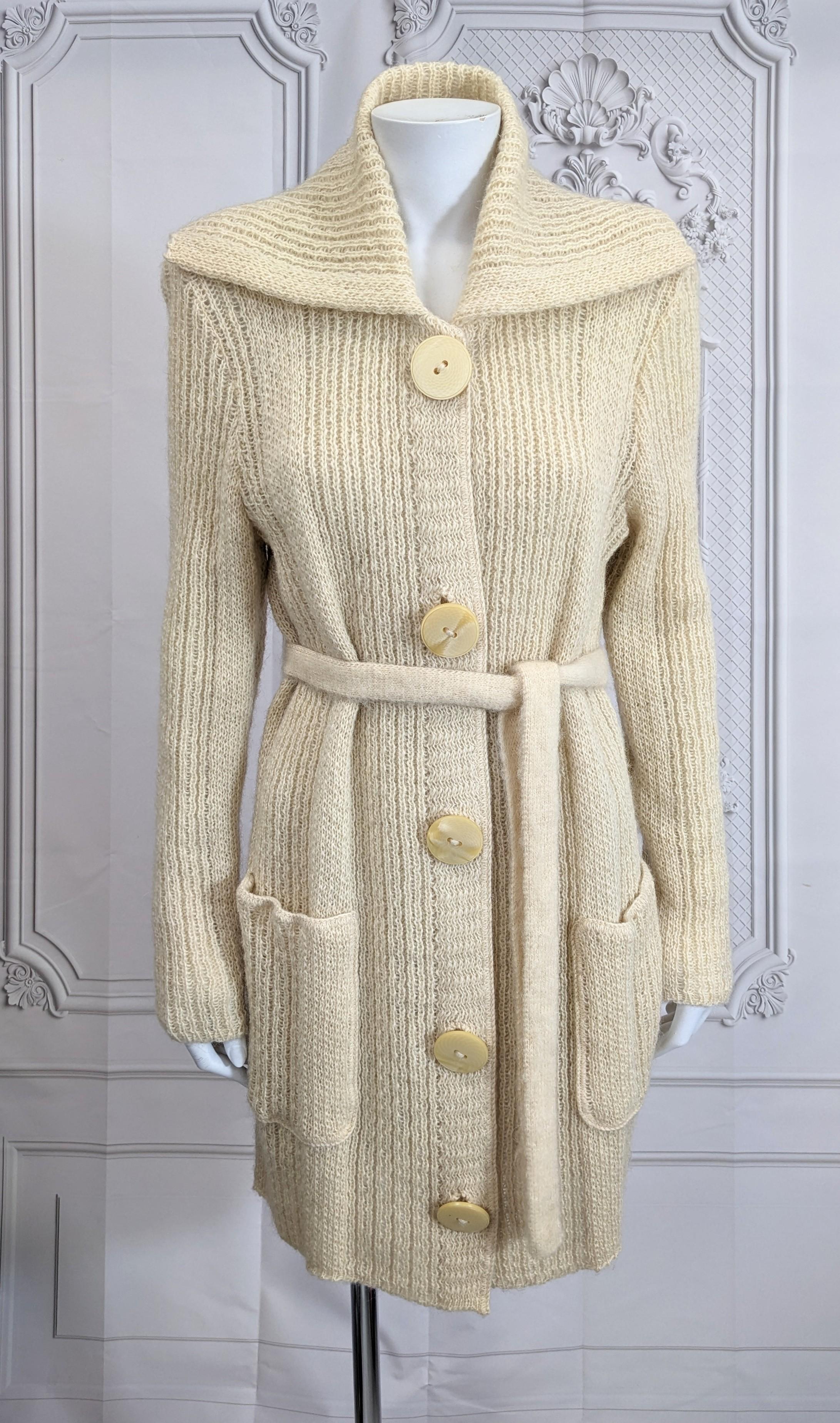 Long Line Ribbed Wool Sweater Cardigan from the 1970's. Channel your inner Ali McGraw with with long cream wool sweater with exaggerated collar, patch pockets and self belt.
Large faceted bakelite buttons. 1970's Italy. Small Size. 