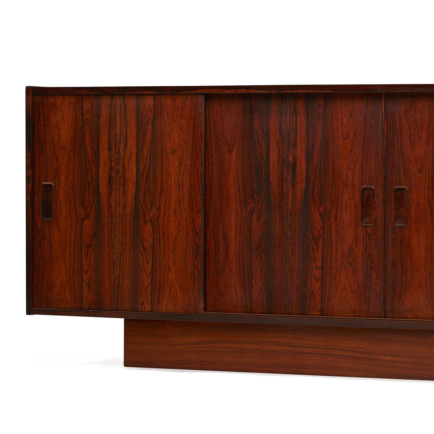Expertly crafted vintage Danish rosewood credenza. The unit features convenient sliding doors that conceal cabinet space at left and right. An uncommon mix of drawers and cabinet space make this piece versatile. Use it as a dresser in the bedroom,